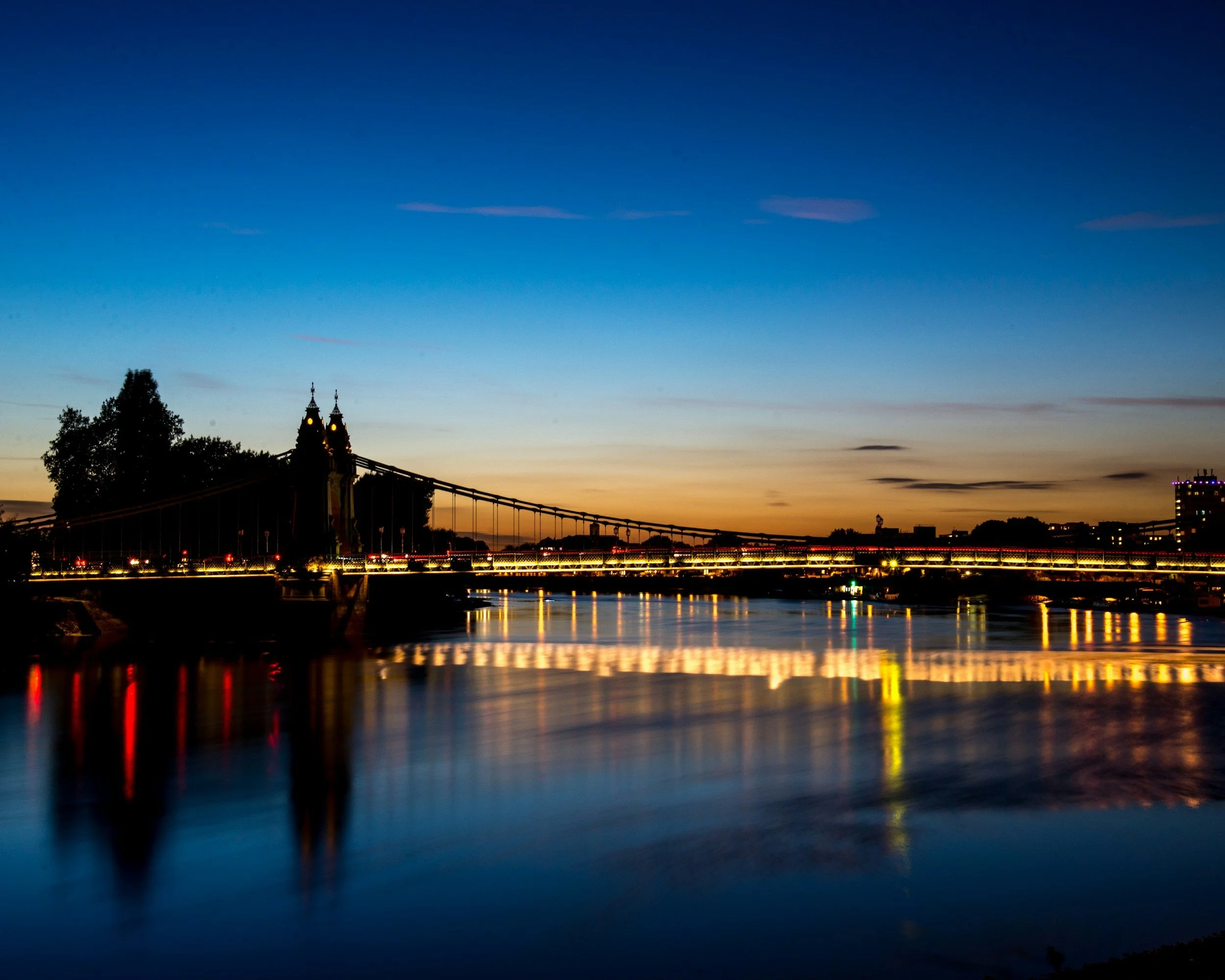 A view of a bridge over water during sunset with a clear sky.