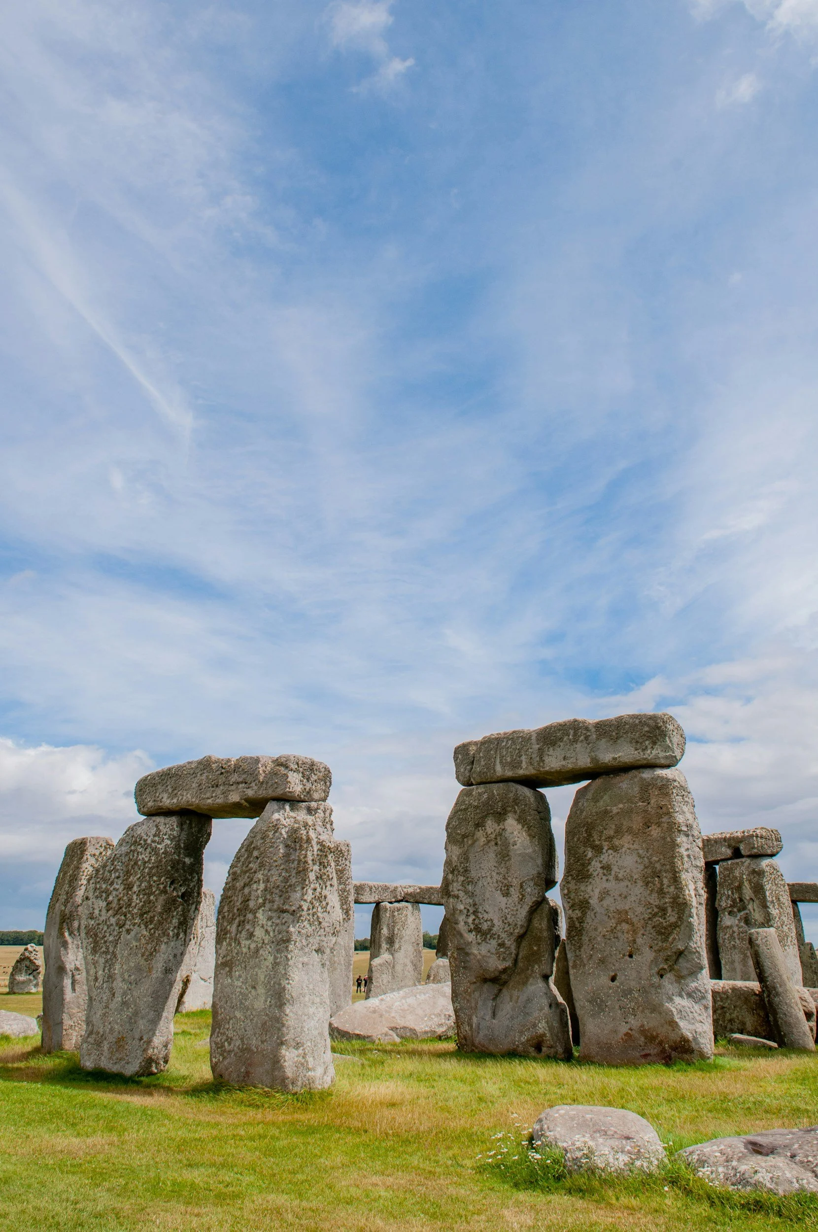 Stone circle with large upright stones and smaller horizontal stones on top, set on grassy land under a cloudy sky at Stonehenge.