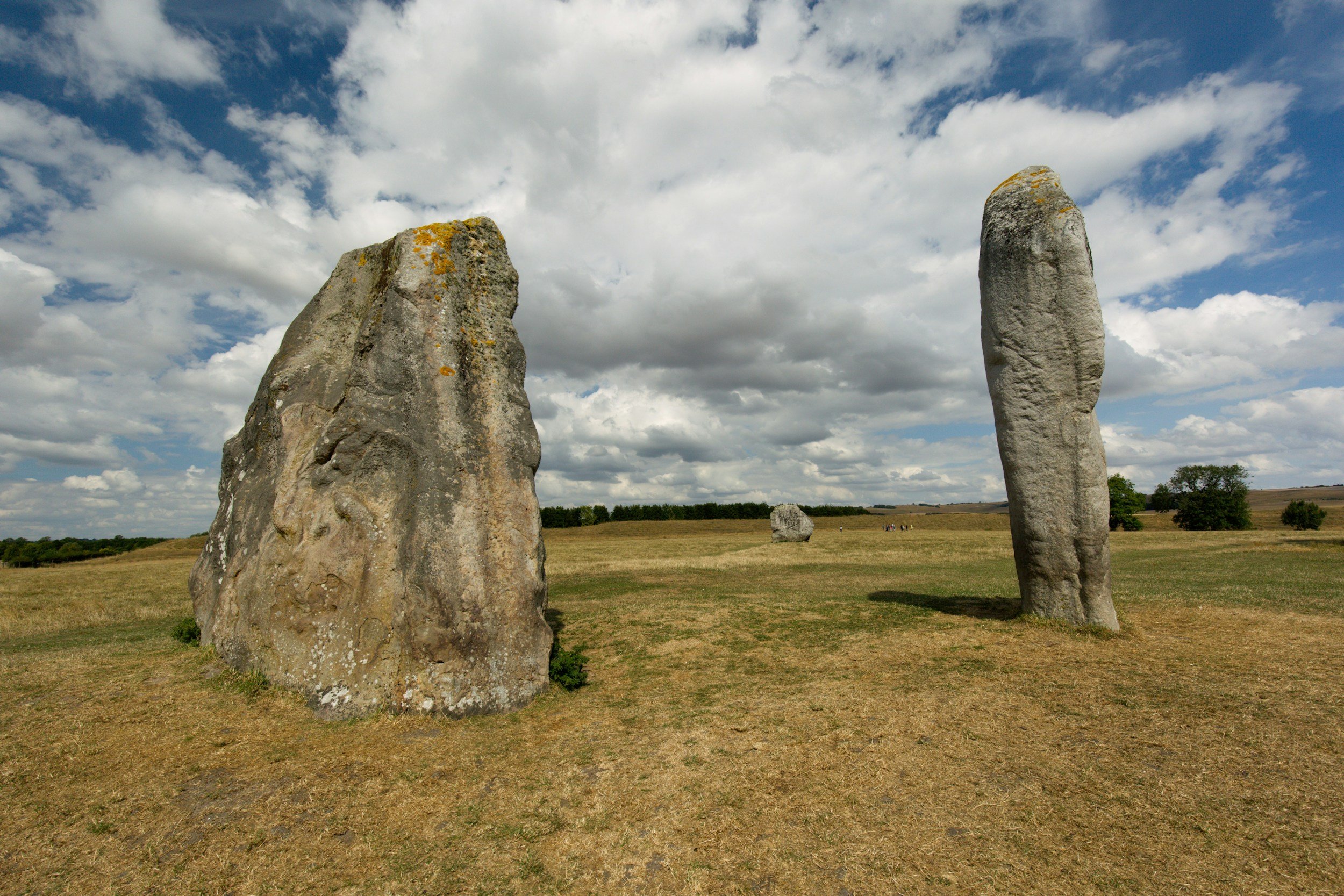 Two large standing stones in a grassy field with a partly cloudy sky overhead.