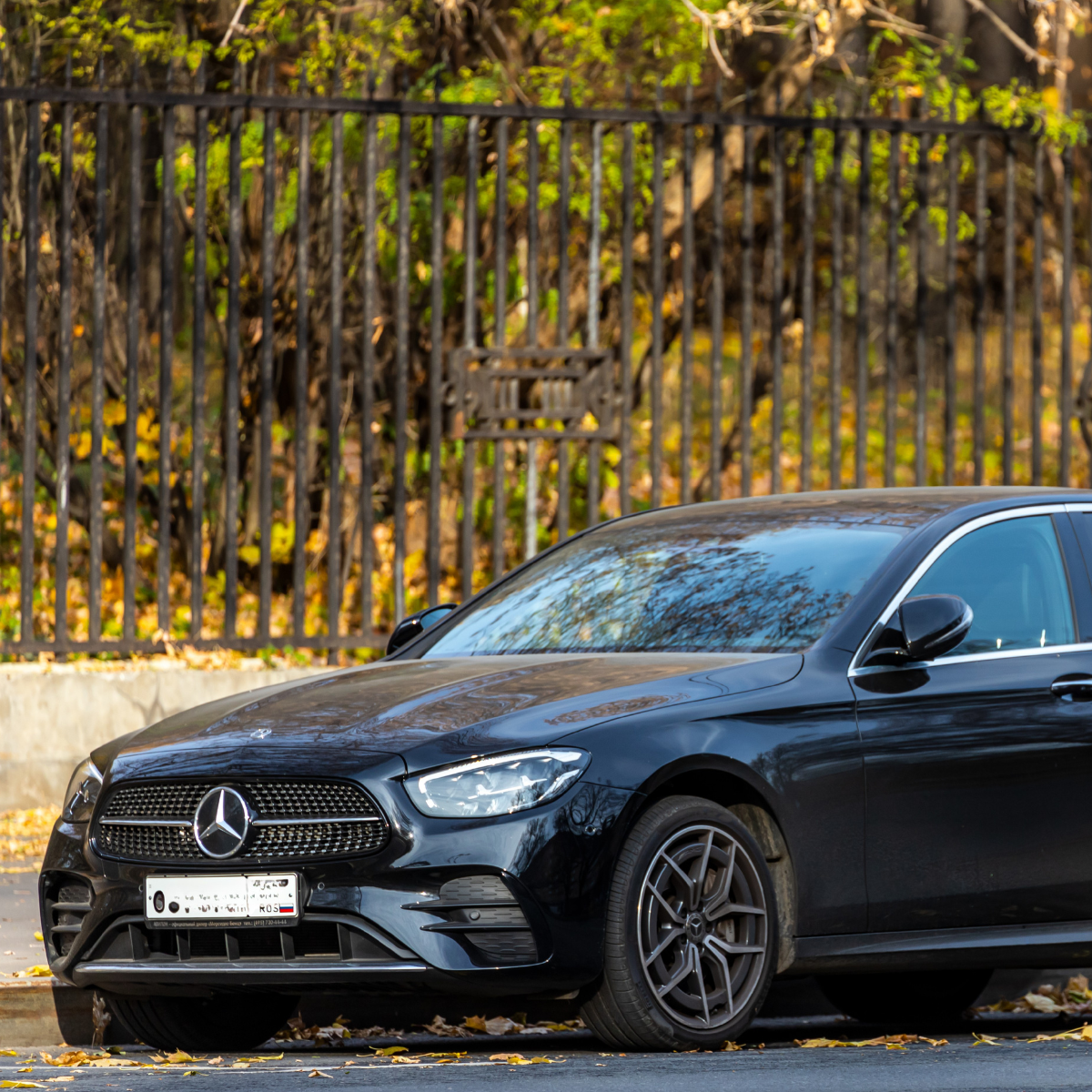 Front view of a black BMW car with a shiny, reflective surface, showing the grille, headlights, and windshield, with reflections of clouds on the hood and windshield.