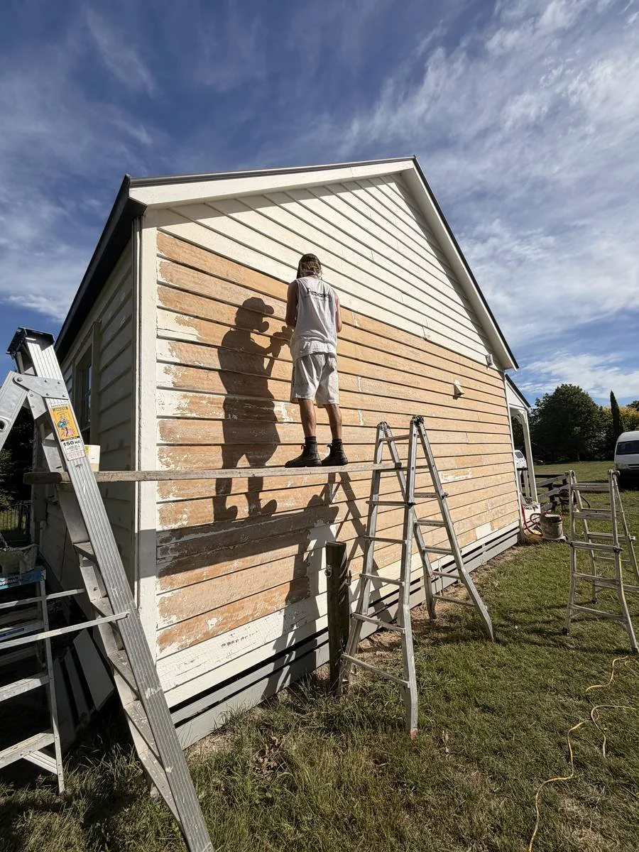painter-on-ladder-exterior-weatherboard-prep-strip.jpg