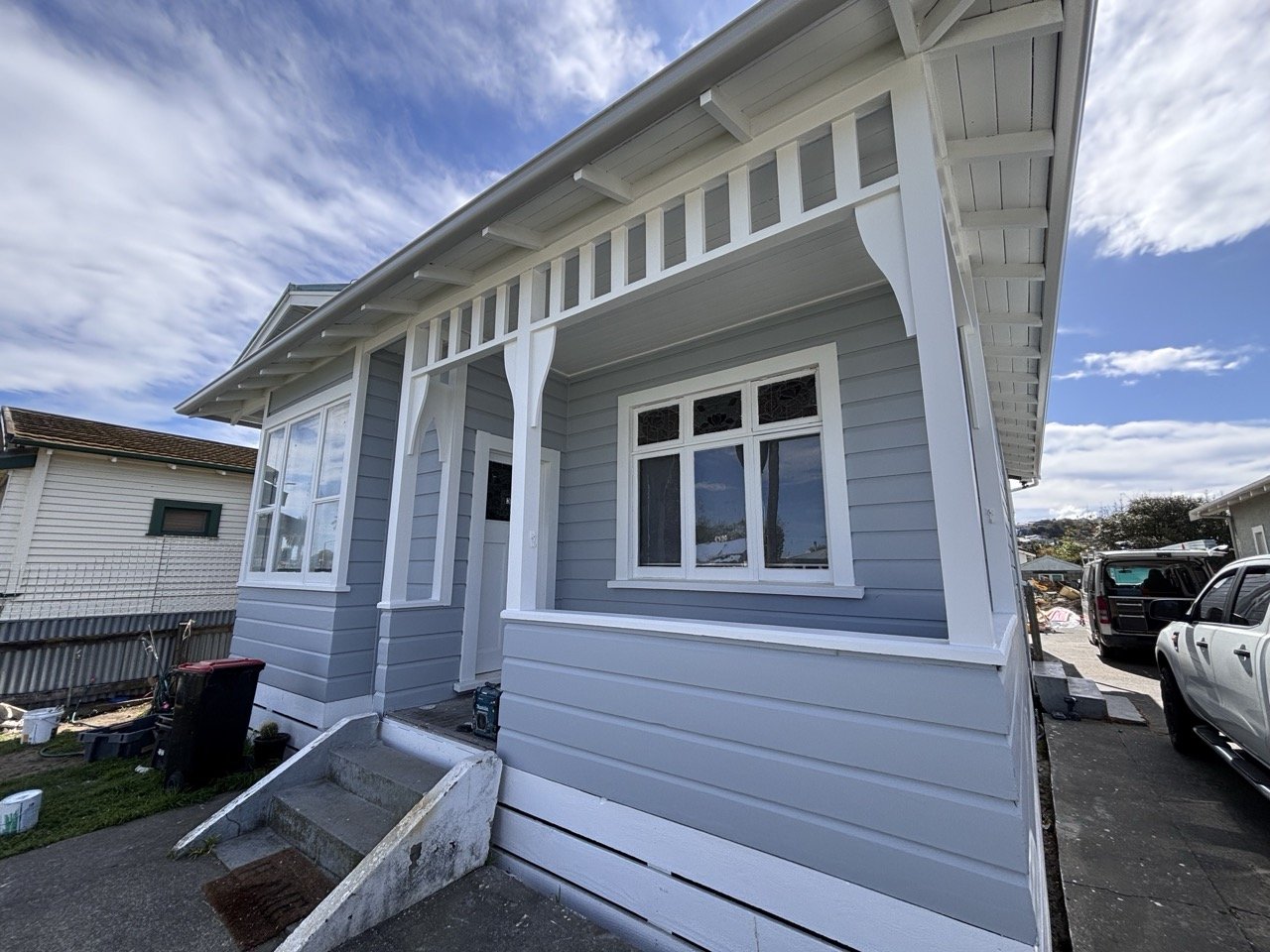 exterior shot of freshly painted character villa showing grey weatherboards and white trims around windows and verandah
