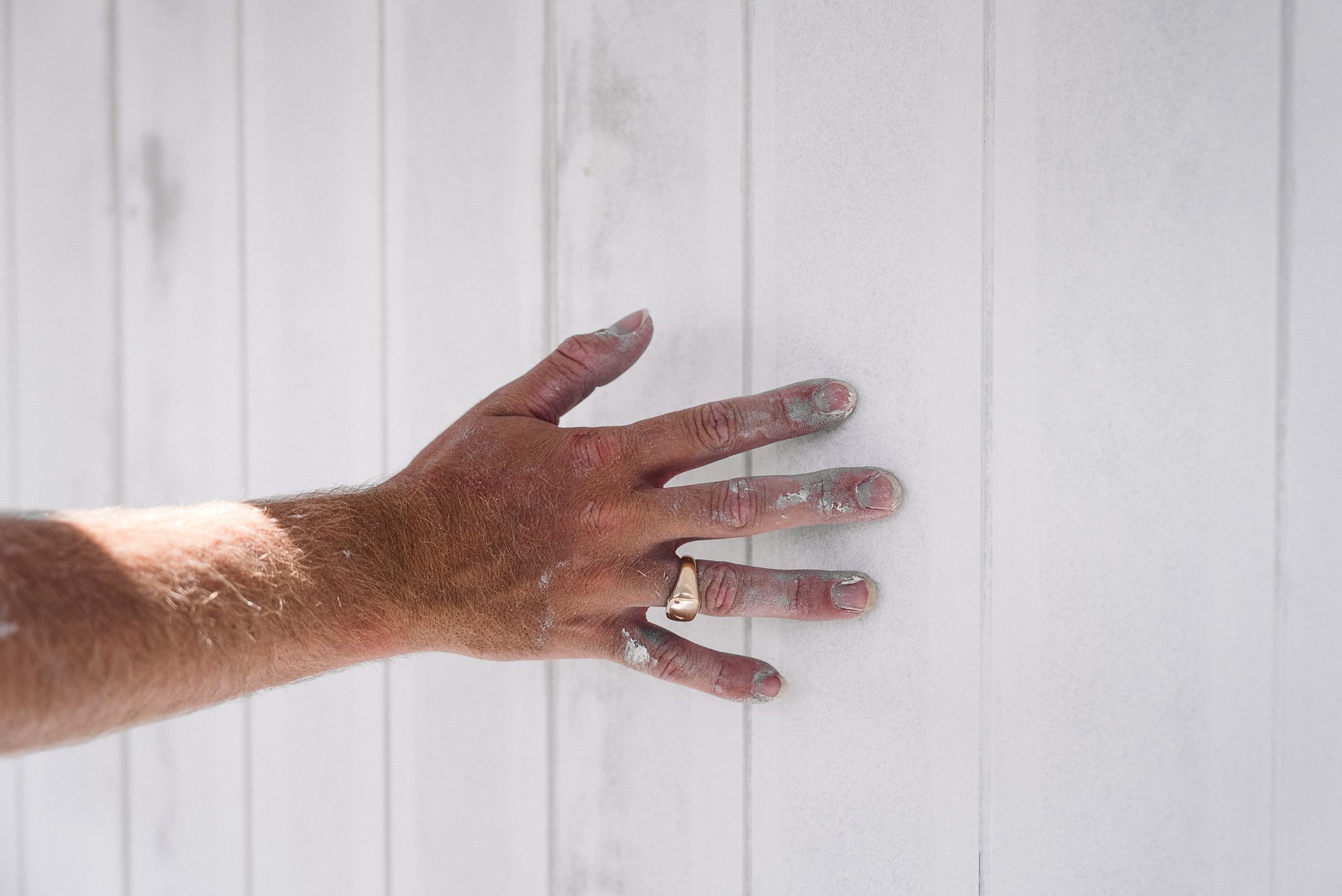 painter-hand-checking-freshly-painted-weatherboard-surface.jpg