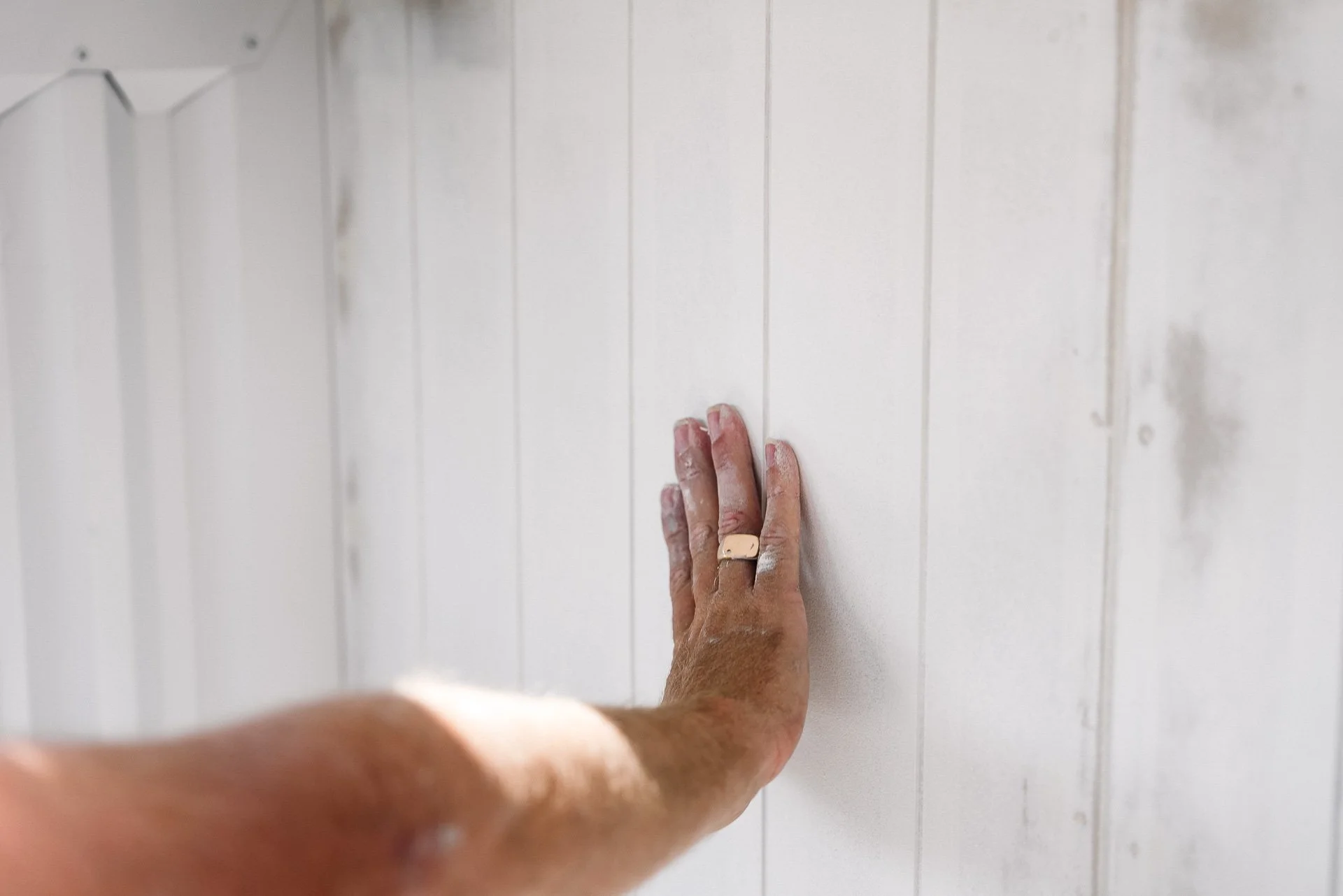 painter-hand-checking-white-weatherboard-surface.jpg