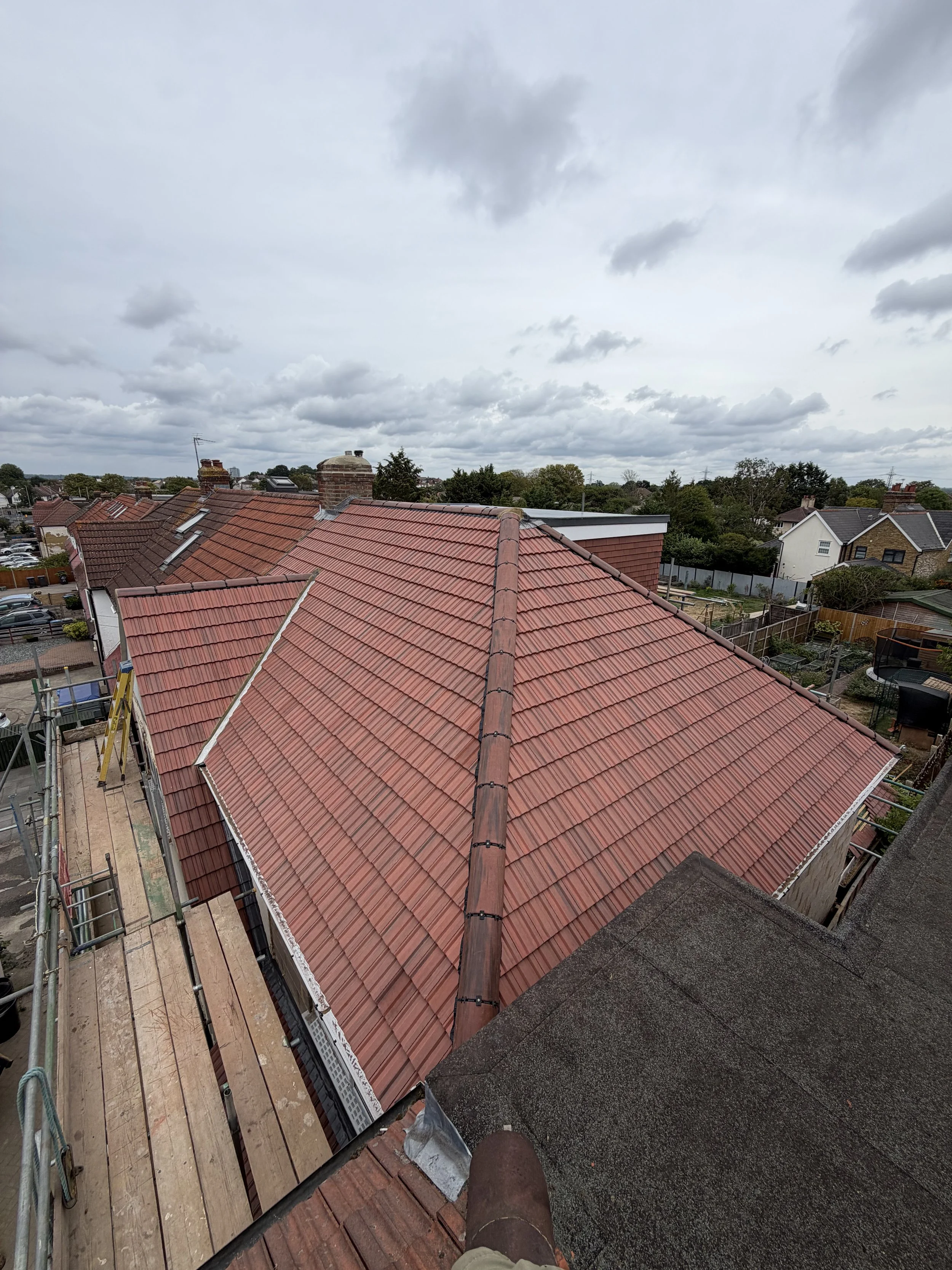 View from a rooftop looking down at neighboring rooftops with overcast sky overhead.