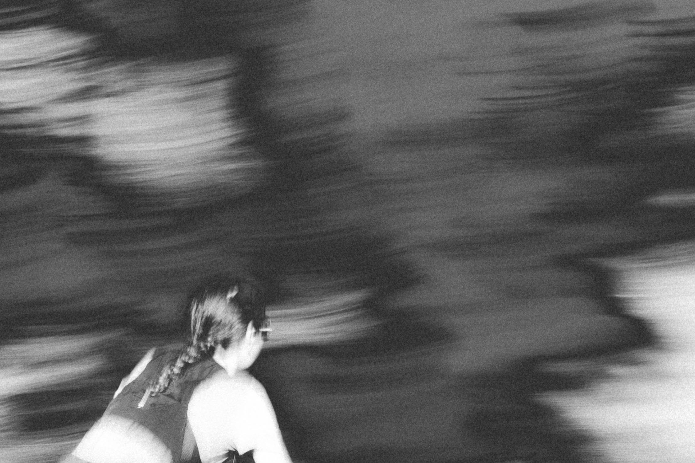 Une personne en jogging court rapidement dans un espace sombre et flou, donnant une impression de mouvement.