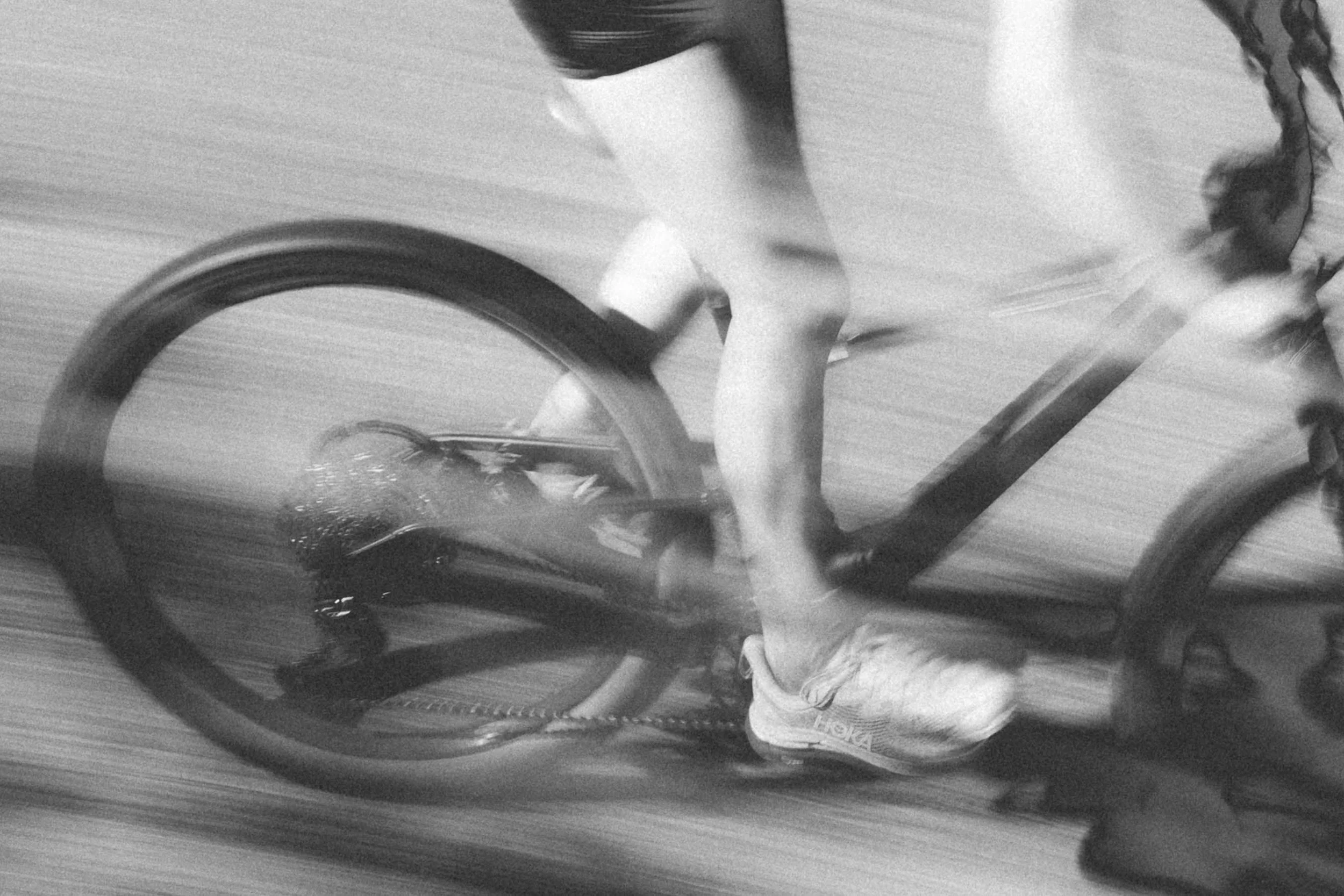 Une personne fait du vélo, vue en mouvement floue, portant des vêtements décontractés et un casque, dans un environnement urbain.