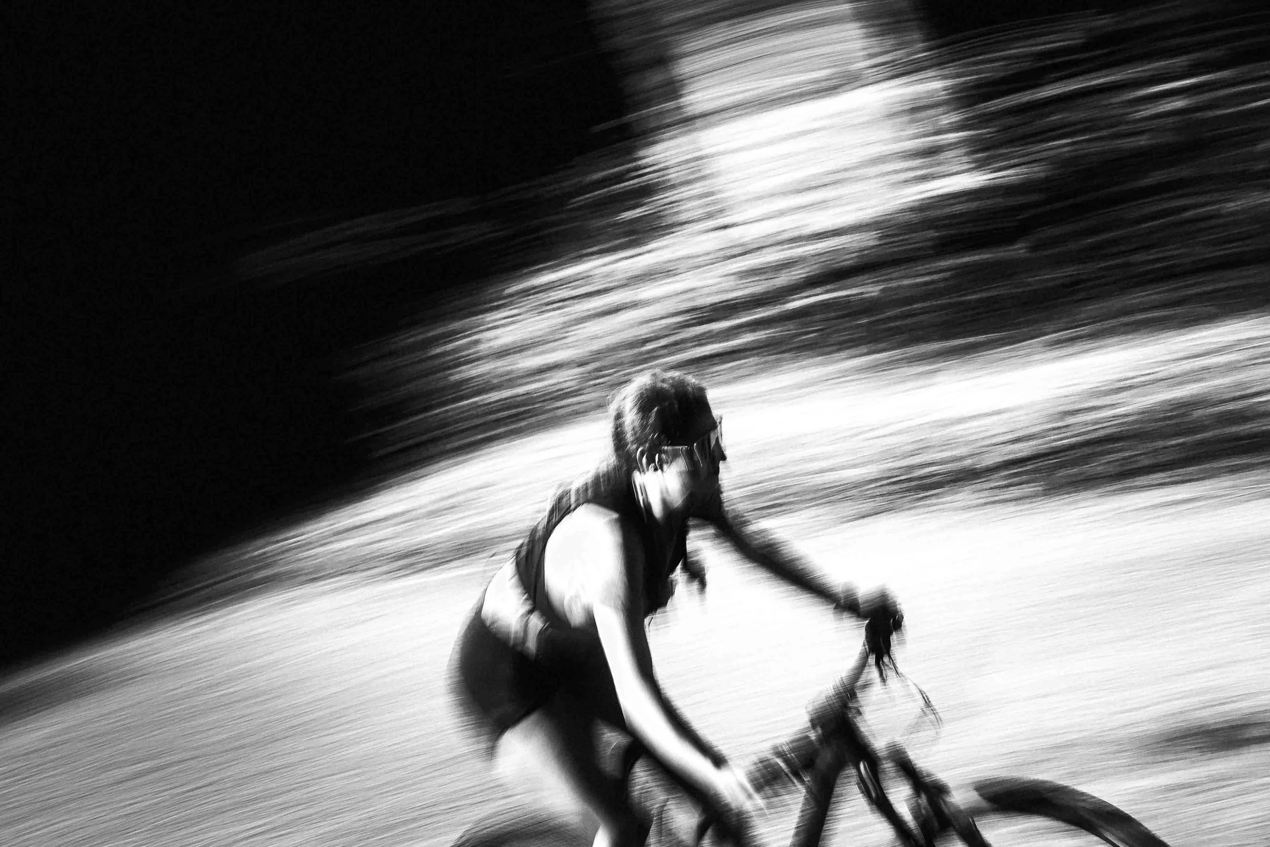Une personne en mouvement sur un vélo, photographie en noir et blanc avec un effet de flou dynamique