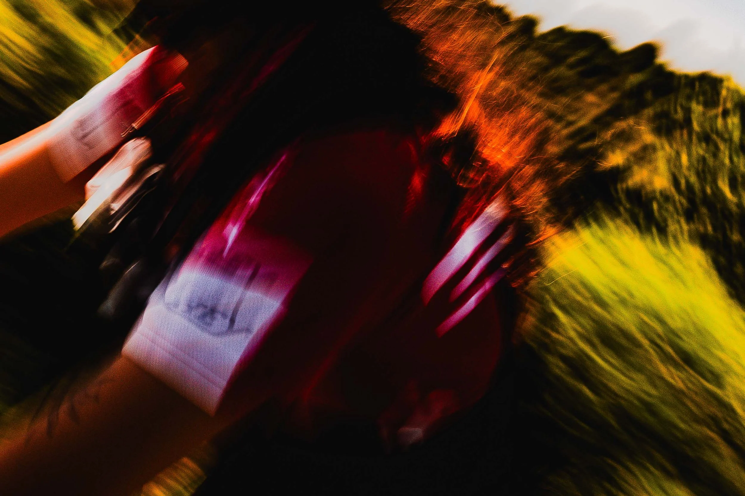 Une photo floue prise en mouvement, avec des lumières rouges, jaunes et vertes visibles, dont certaines proviennent d'une cycliste 
