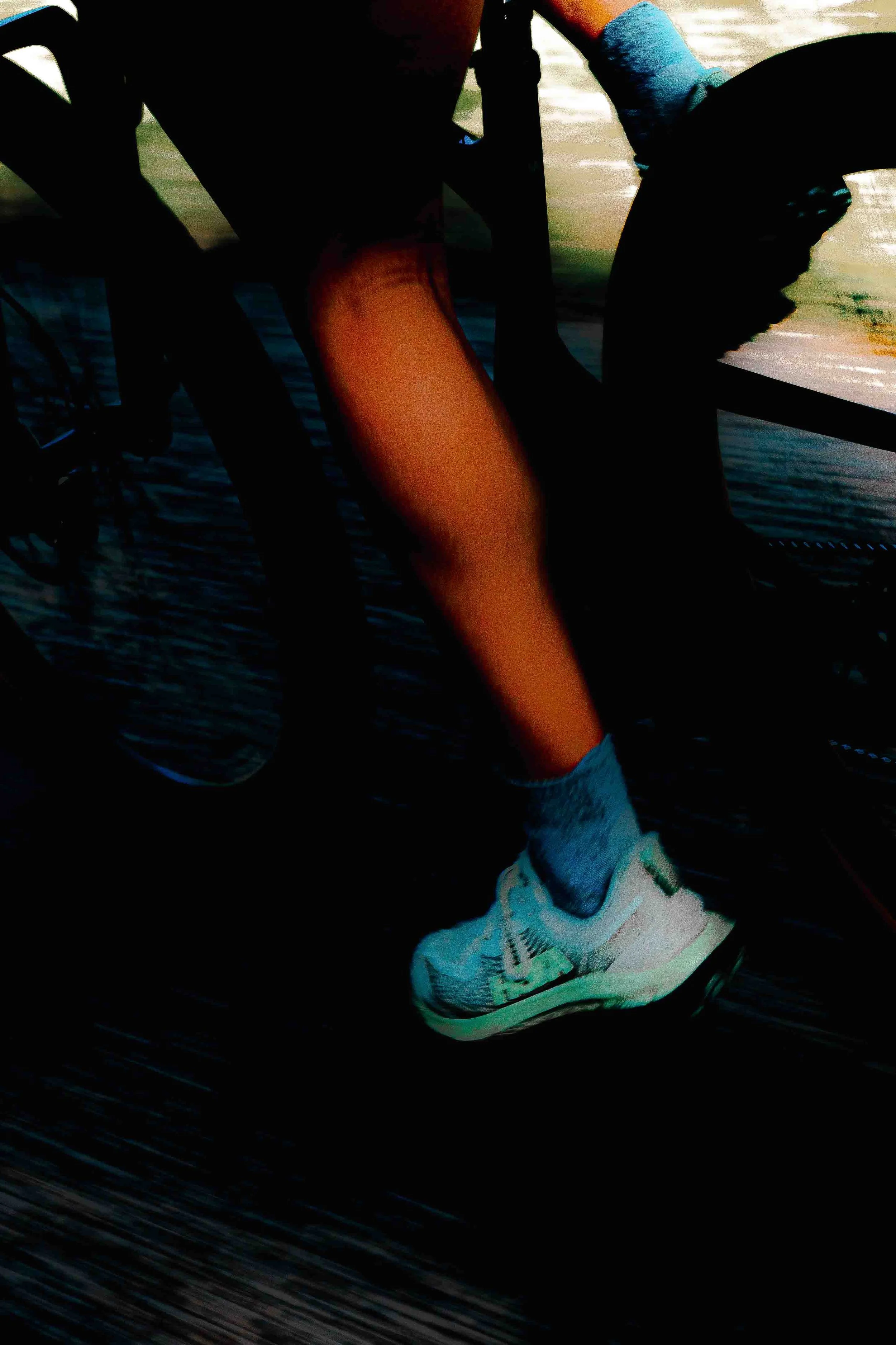 Ambassadeur de running portant des chaussures Adidas, en mouvement, sur une surface sombre et mouillée.