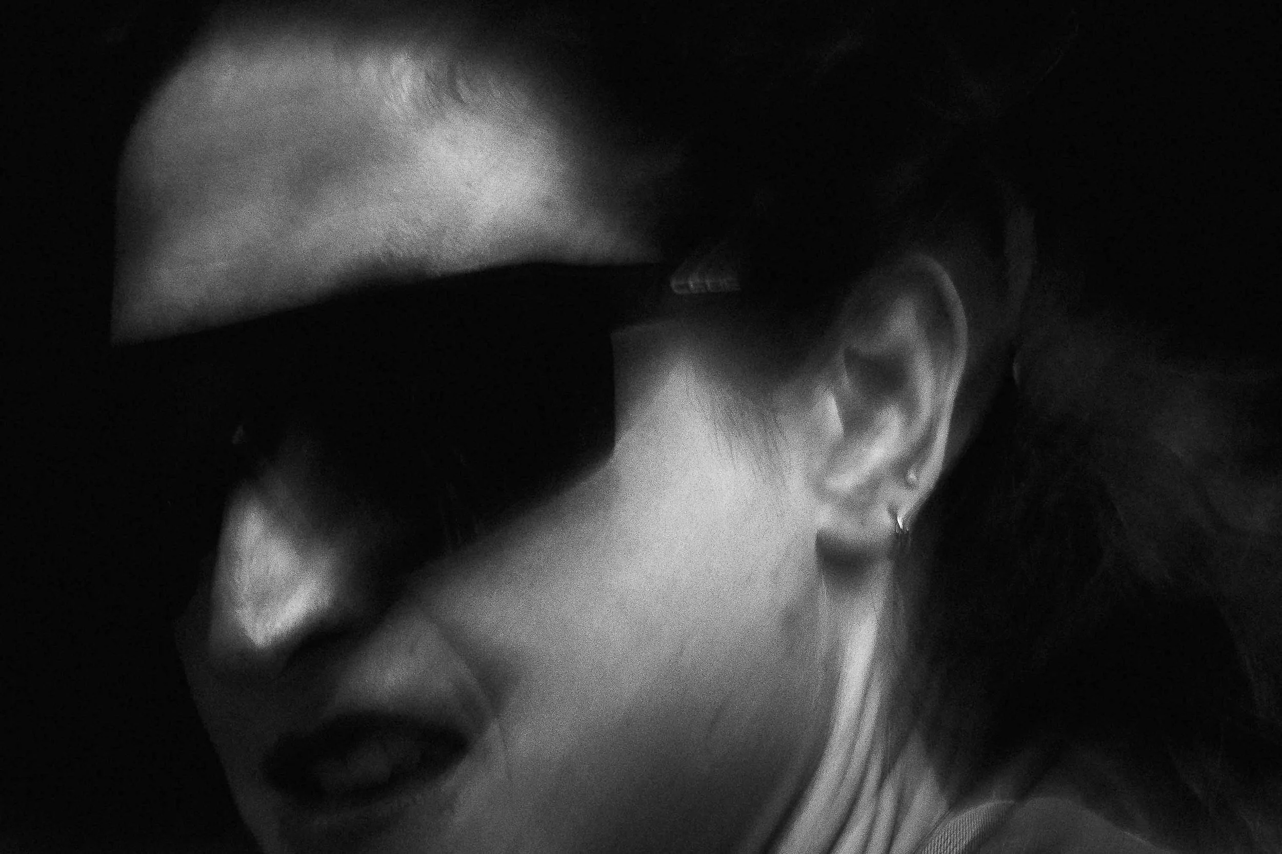 Un visage d'une personne en noir et blanc, avec un œil visible, que l'on tient par la main.