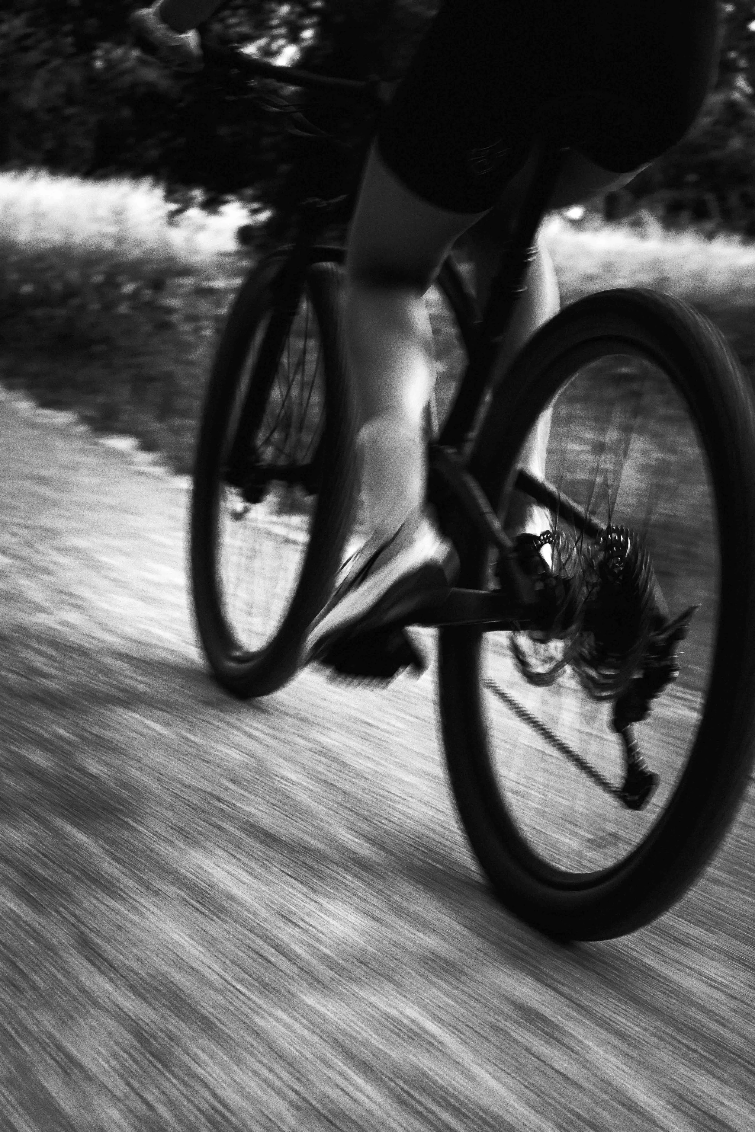Une personne faisant du vélo, vu de près, en mouvement, en noir et blanc, probablement en ski ou en montagne.