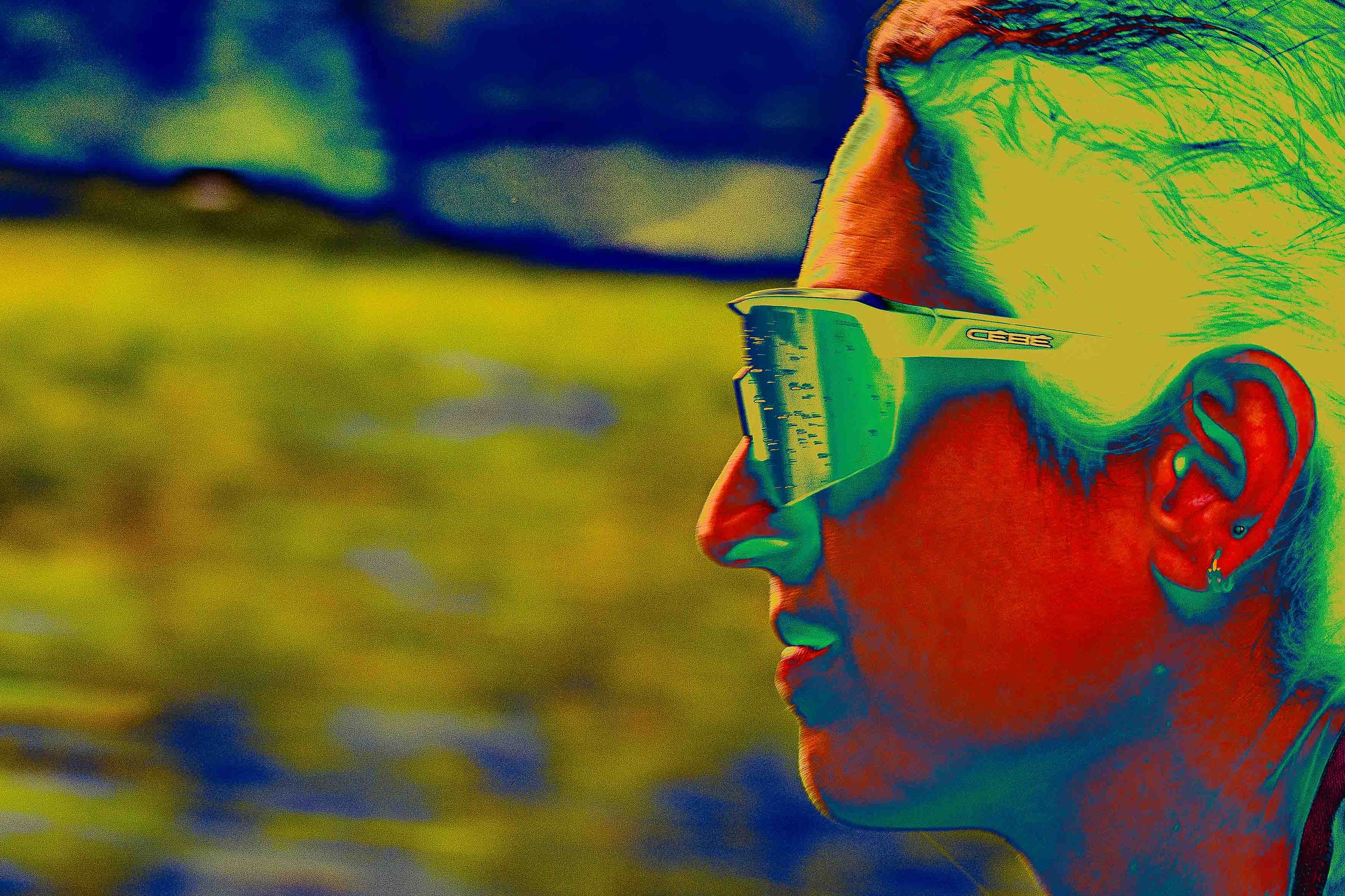 Un profil d'une personne portant des lunettes de soleil, rendu en style artistique avec des couleurs vibrantes et un effet de thermographie.