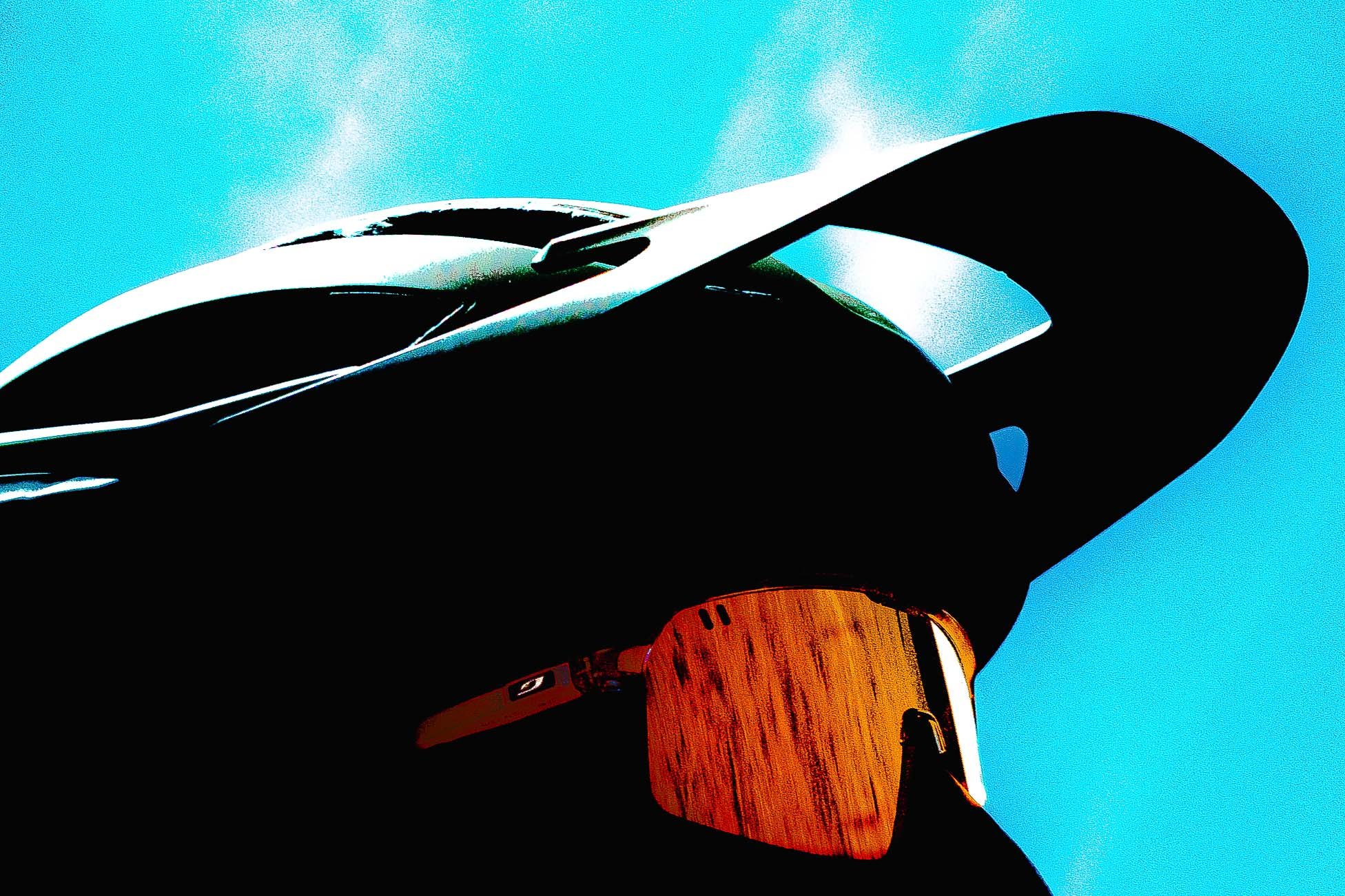 Stylo plume noir posé sur un fond en bois, avec un motif de style capot de voiture de course et un ciel bleu clair derrière.