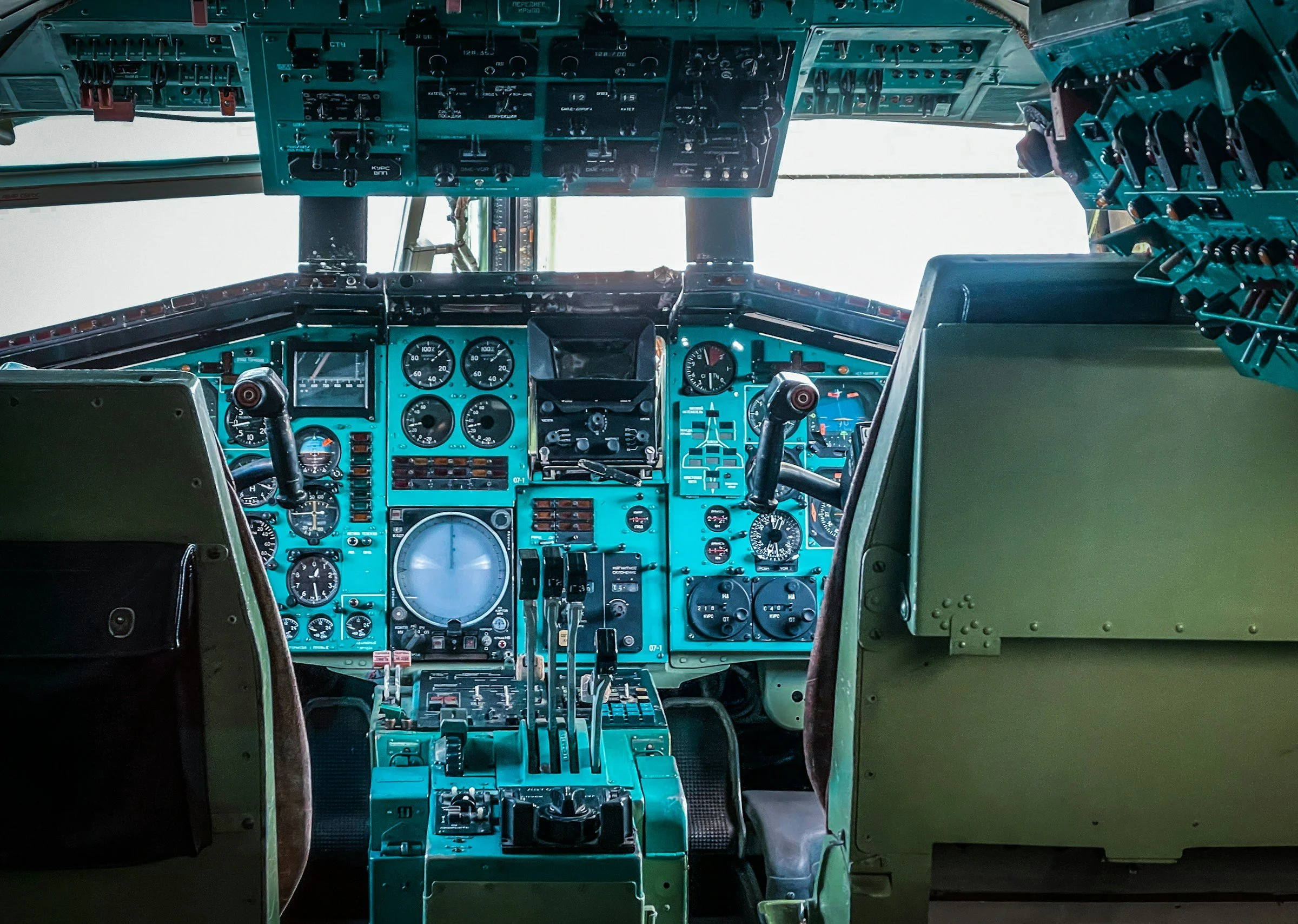 Interior of an aircraft cockpit with various gauges, switches, and control sticks.
