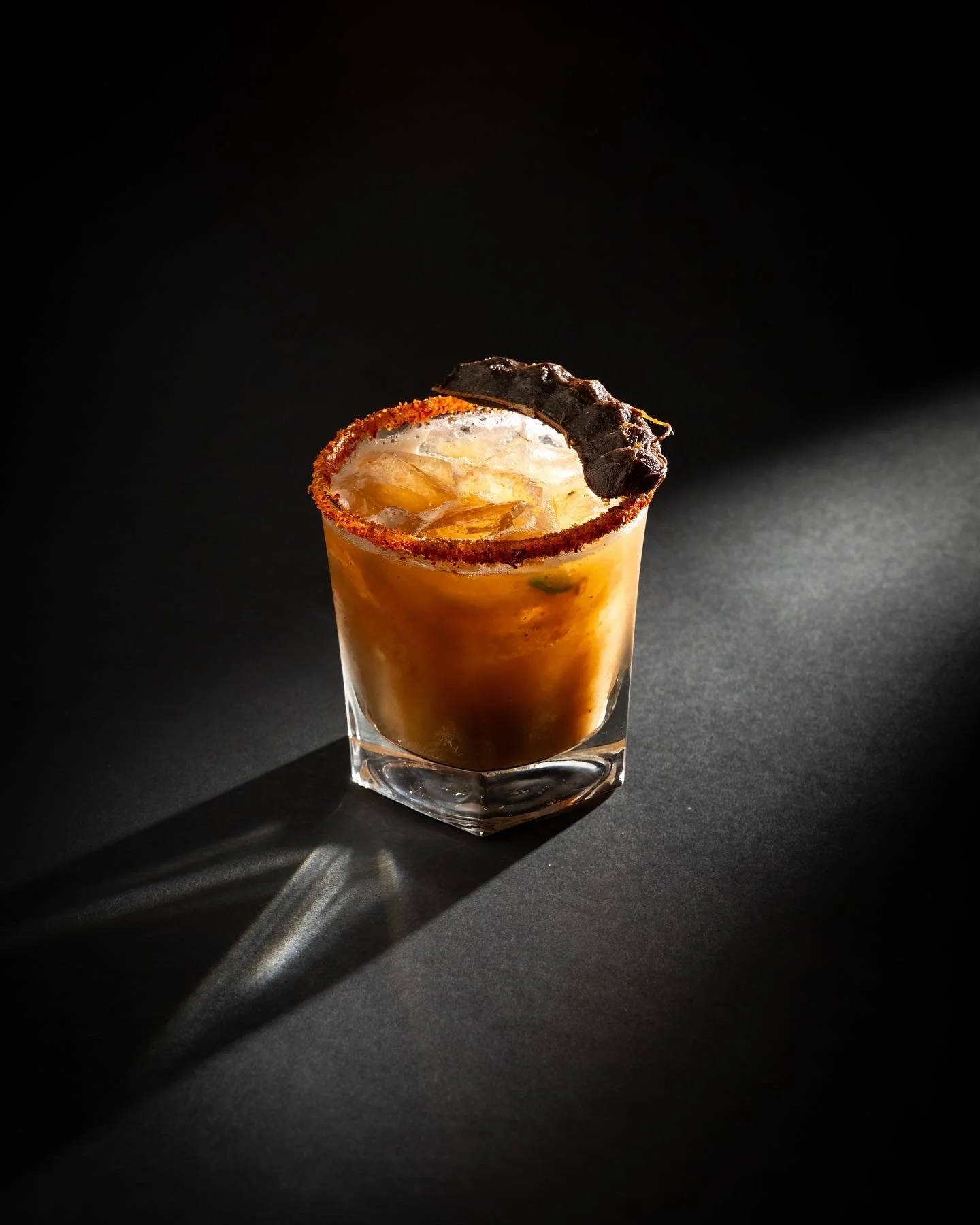 A tamarind margarita set against a dark background.