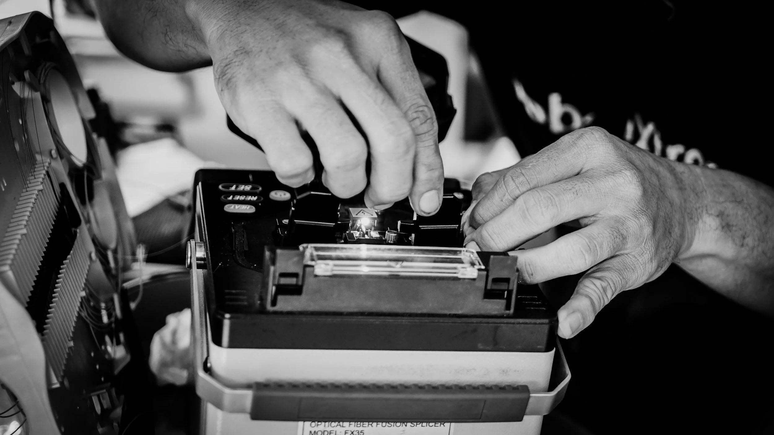 Fiber-optic technician operating a fusion splicer for telecom network installation.
