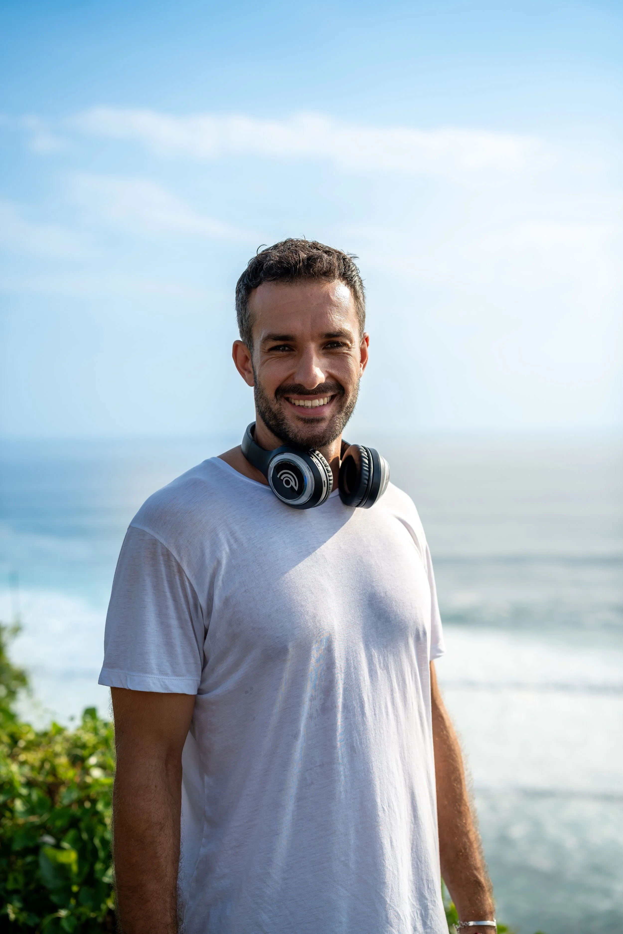 Remote mountain landscape with snow-capped peaks in the background, rolling green hills in the foreground, and a modern, minimalistic house.