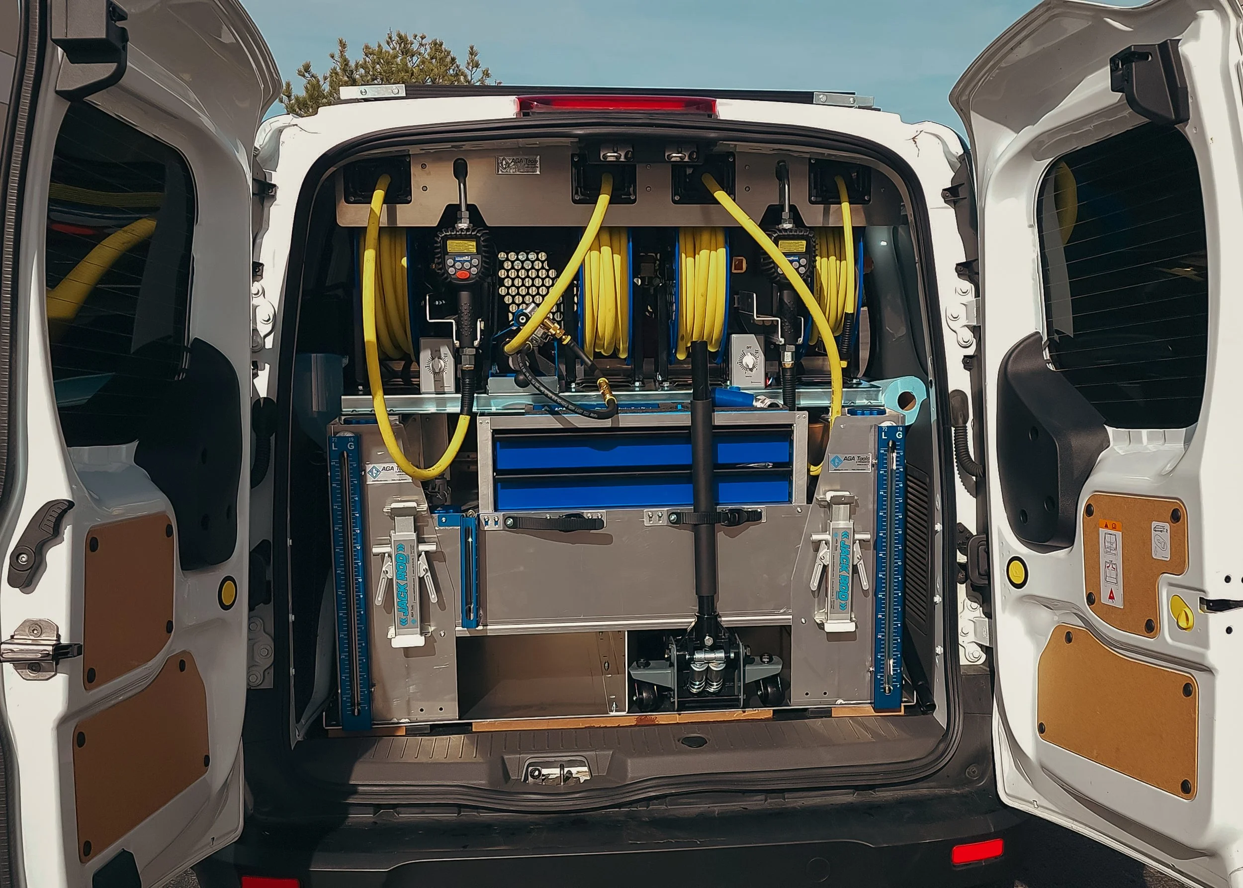 The back of a utility vehicle showing organized equipment, including yellow hoses, electronic devices, and blue storage drawers.