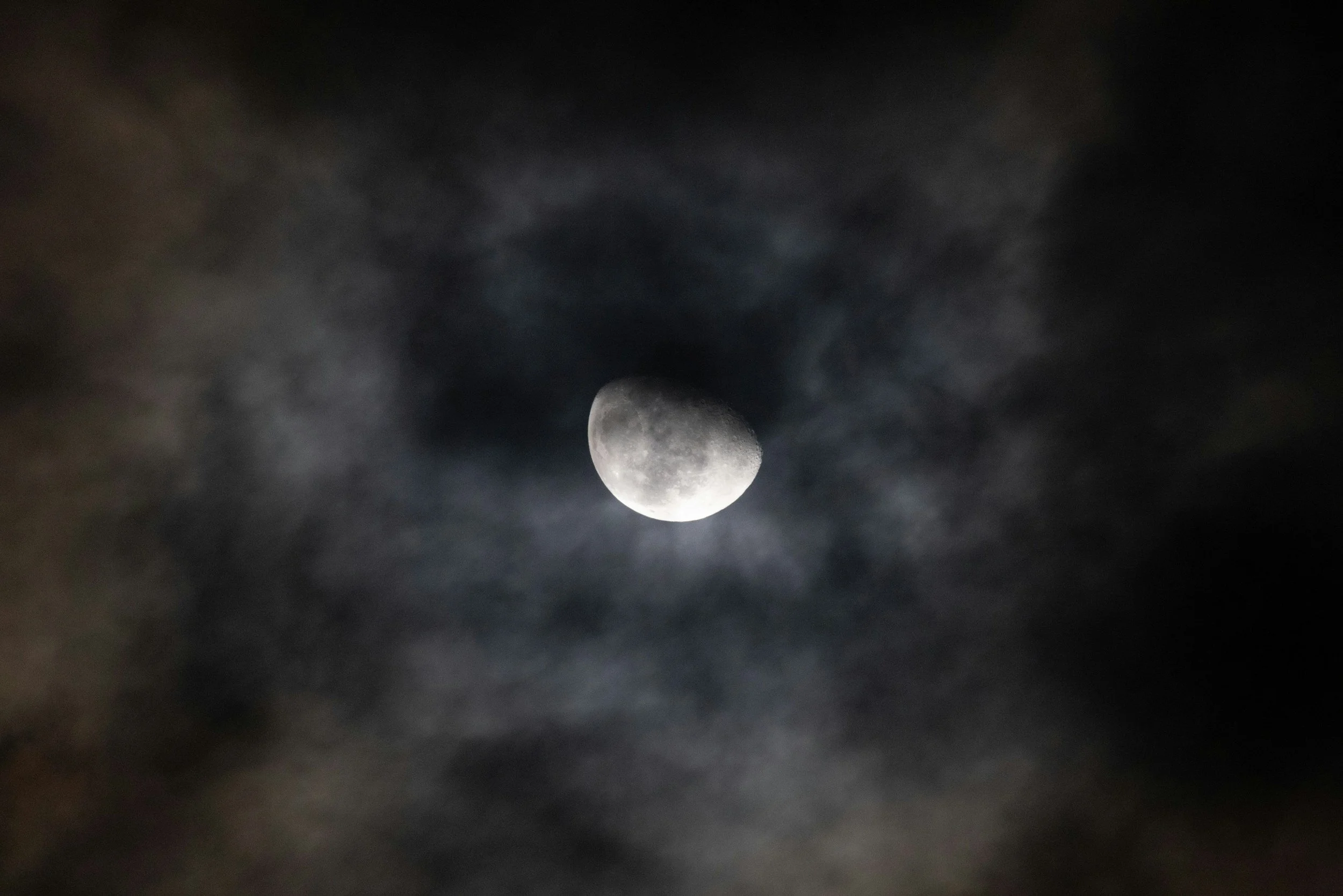 a photo of dark clouds obscuring a full moon