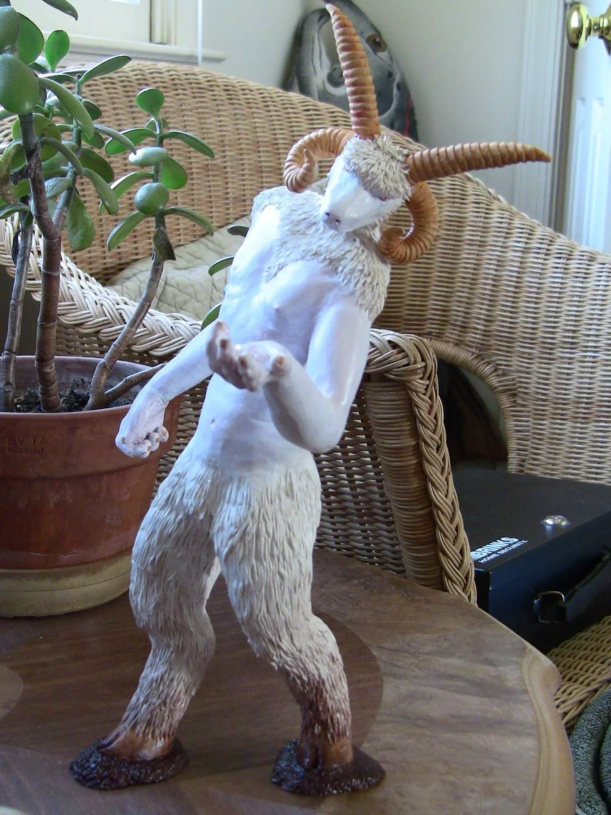 Small sculpture of a goat-headed faun with human torso and animal head/legs, four horns, all white