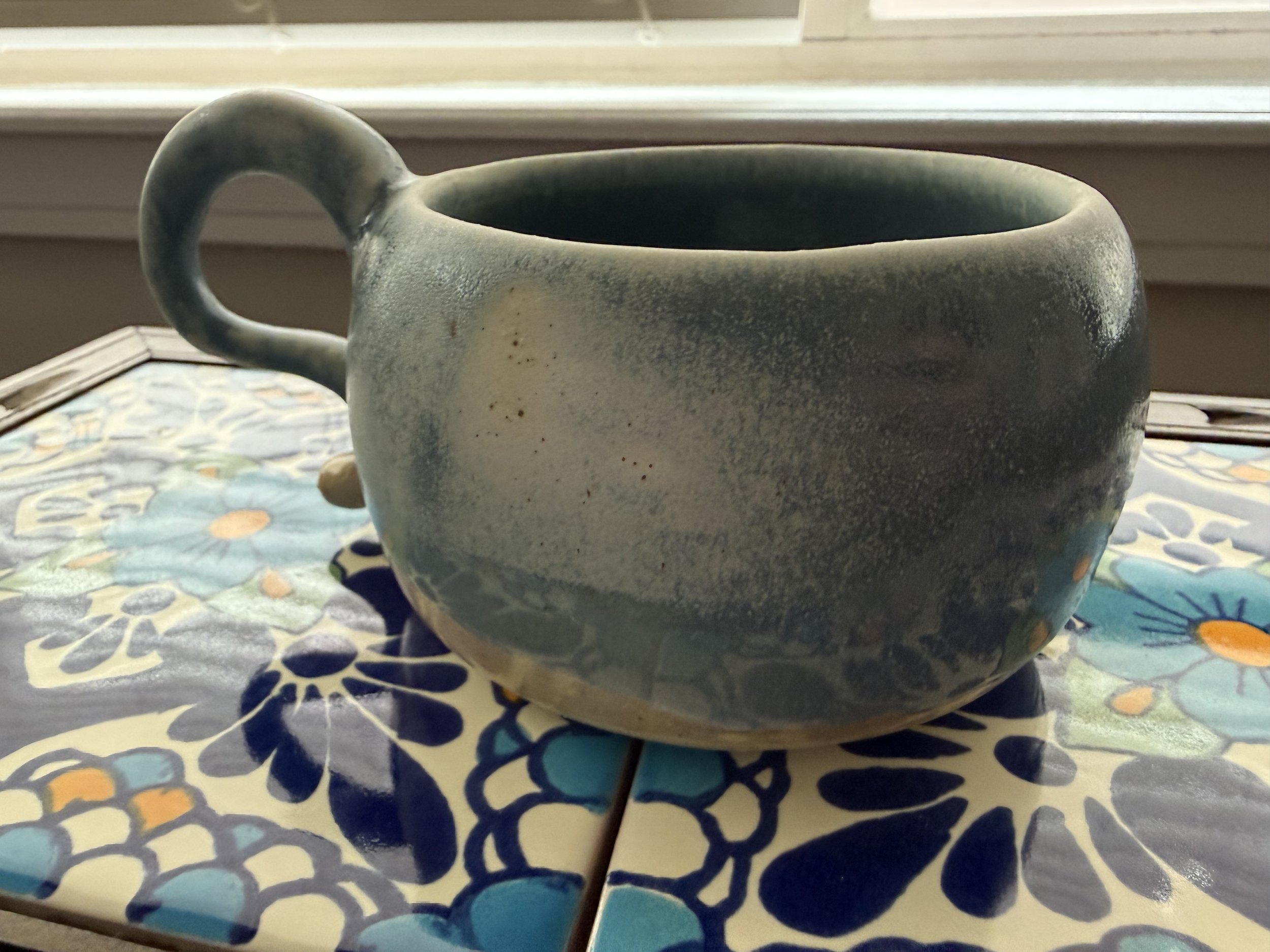 Outside of a small mug with cream and blue glaze