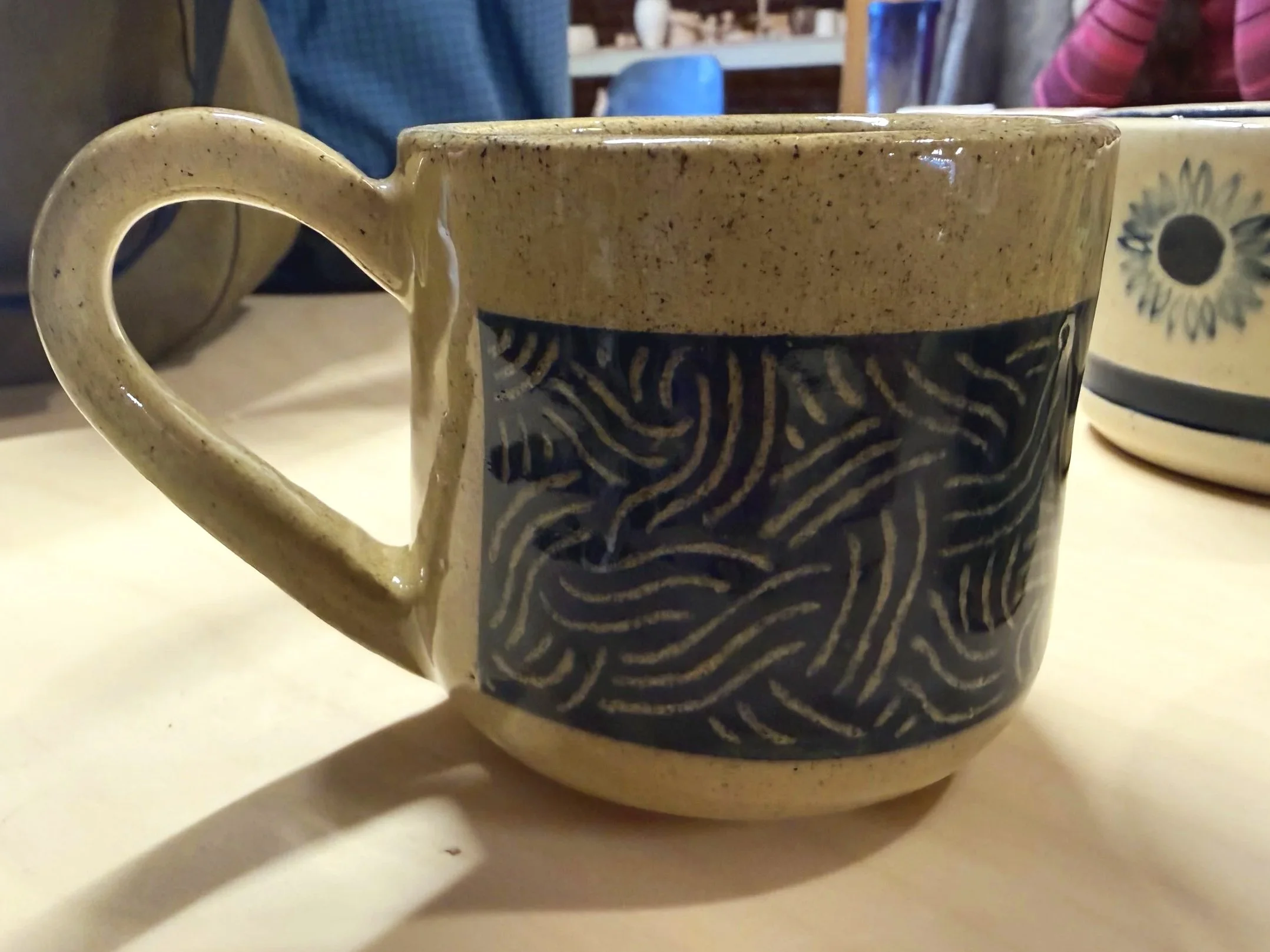 Small ceramic espresso mug decorated with a blue panel carved with a wavy line pattern