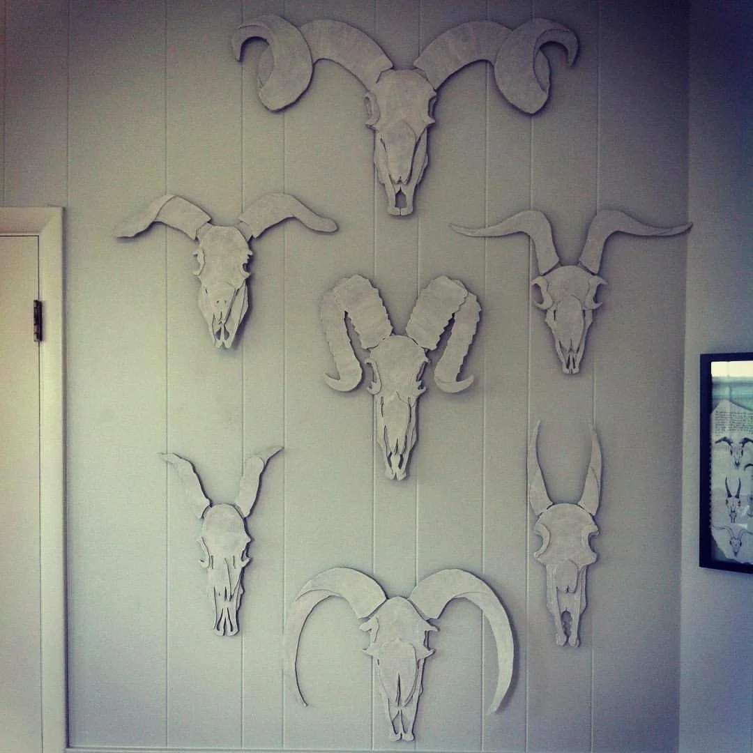 Seven recycled cardboard goat skull reliefs painted white