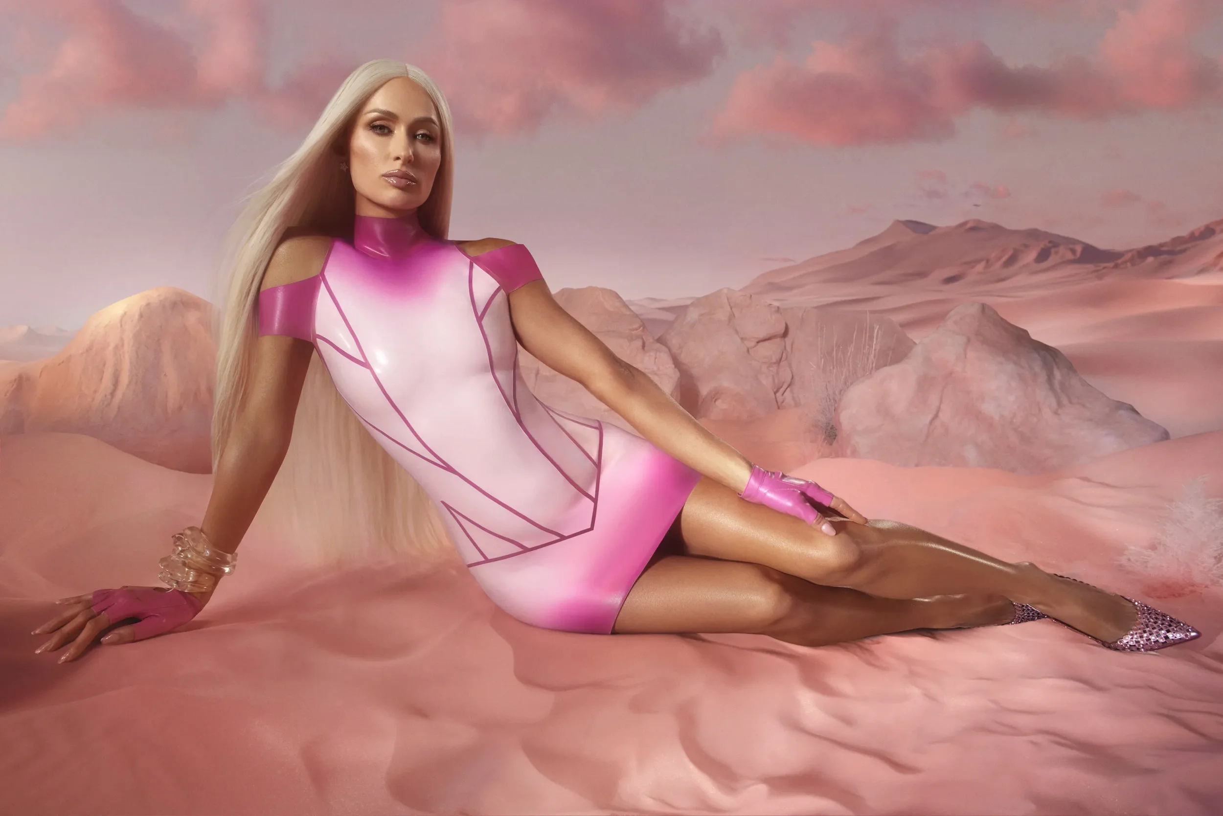 A woman with long blonde hair sitting on pink terrain, wearing a shiny pink and white futuristic dress with shoulder cutouts, pink gloves, and glittery high heels, with a pink-toned landscape and mountains in the background.