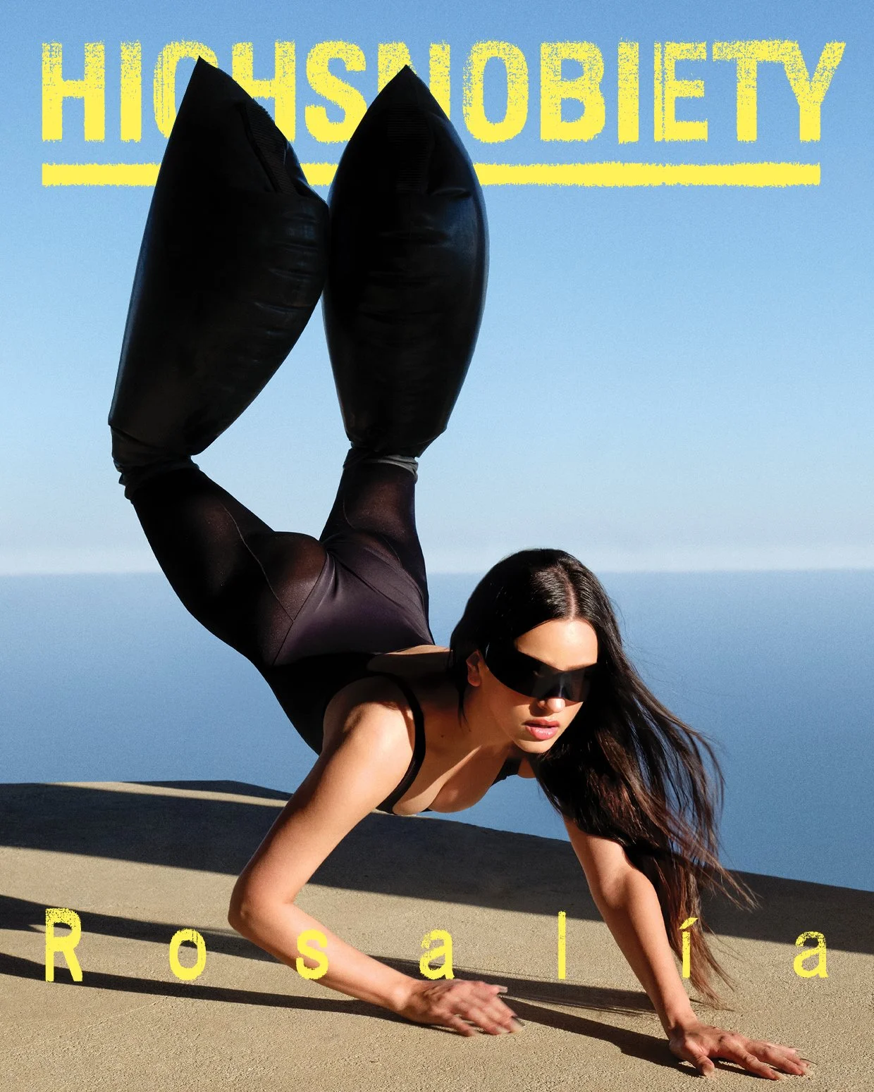 A woman dressed in black exercise clothes performs an advanced yoga pose on sand with a body armor mask, with a background of ocean and blue sky. The words 'HIGH SOBIETY' are at the top in yellow text, and 'Rosália' is at the bottom in yellow text.