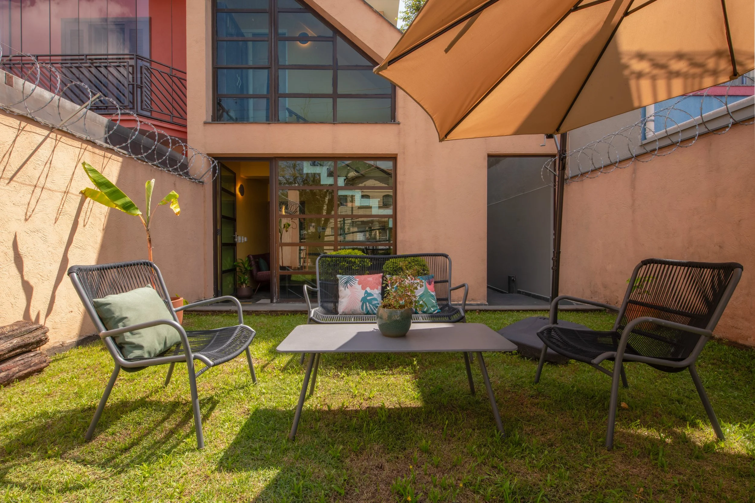 Assentos e guarda sol na Varanda Leda da Casa Cuia em Perdizes, ambiente externo para trabalho, leitura e contemplação.