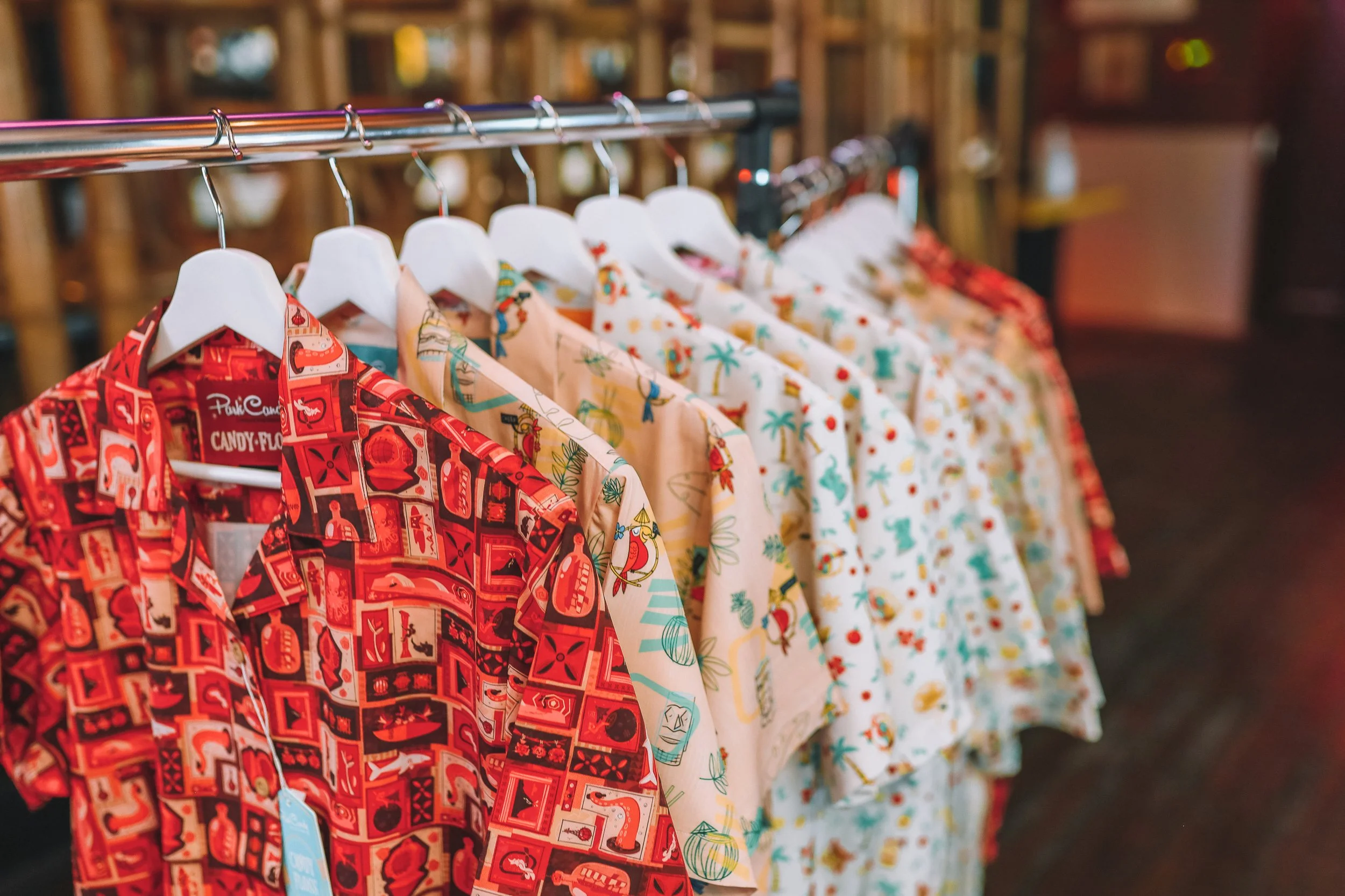 Hawaiian shirts with Christmas and tropical themes hanging on a rack in a store.