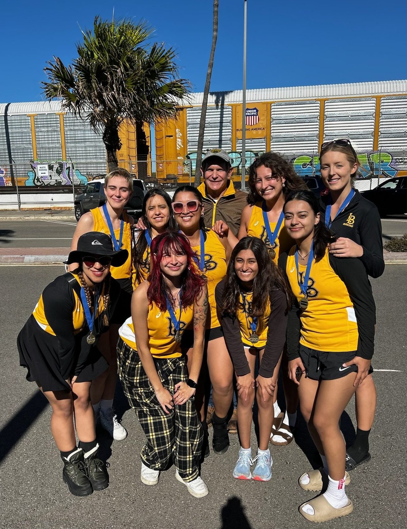 The Women’s Crew pose with their medals and coach.