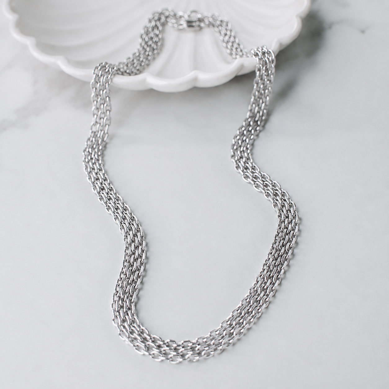 House of Avorio Luna Italian Link Strap Necklace in polished silver stainless steel featuring a multi-strand Italian chain design on a white marble background.