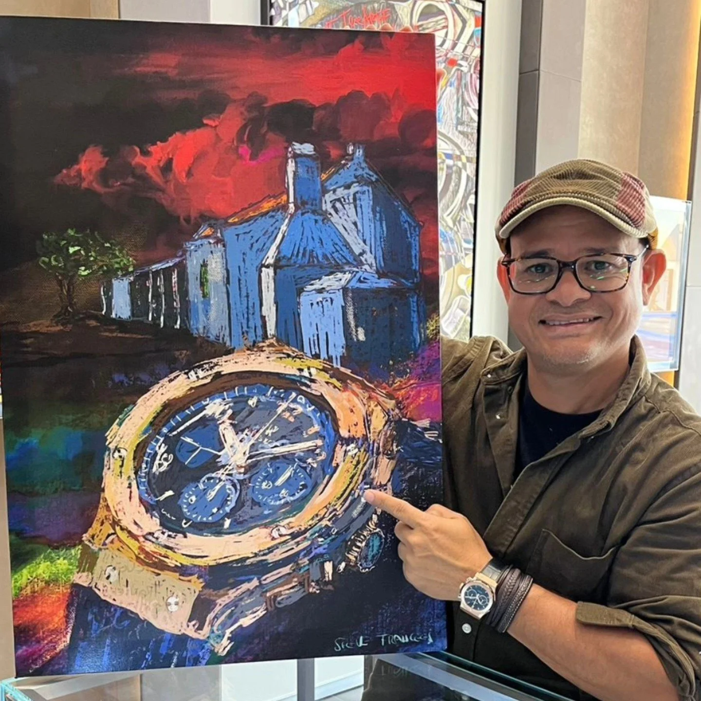 A man wearing glasses, a cap, and a brown jacket pointing to a colorful painting of a watch with a blue face, set against an abstract background of a house and sky.