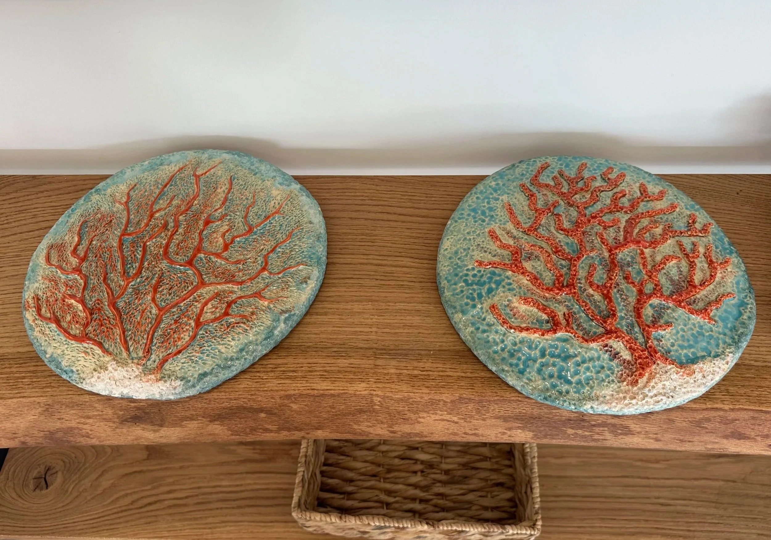 Two decorative round plates with coral designs, placed on a wooden surface.