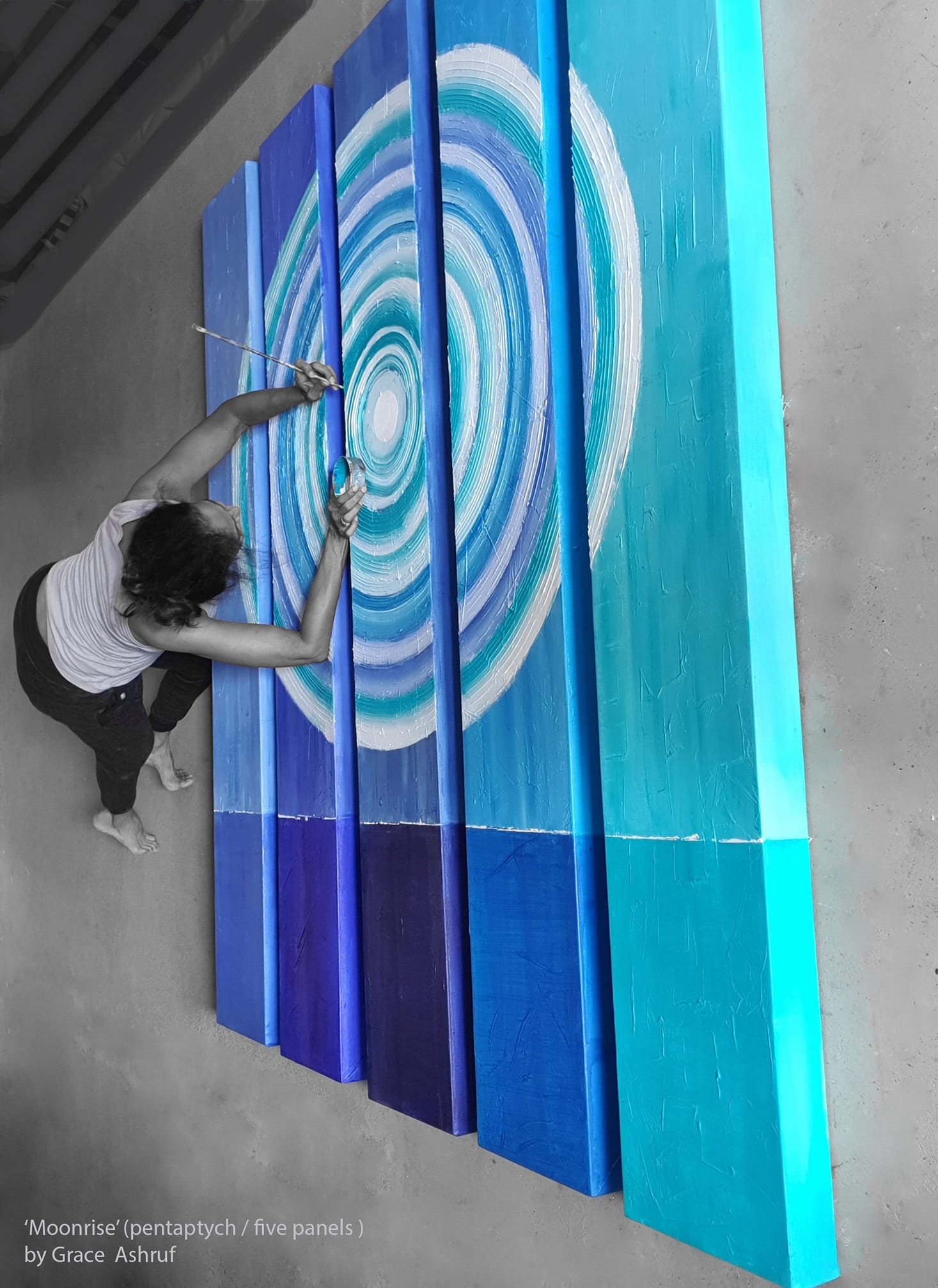 An artist painting a large, five-panel pentaptych titled 'Moonrise' with abstract circular patterns in shades of blue and white.