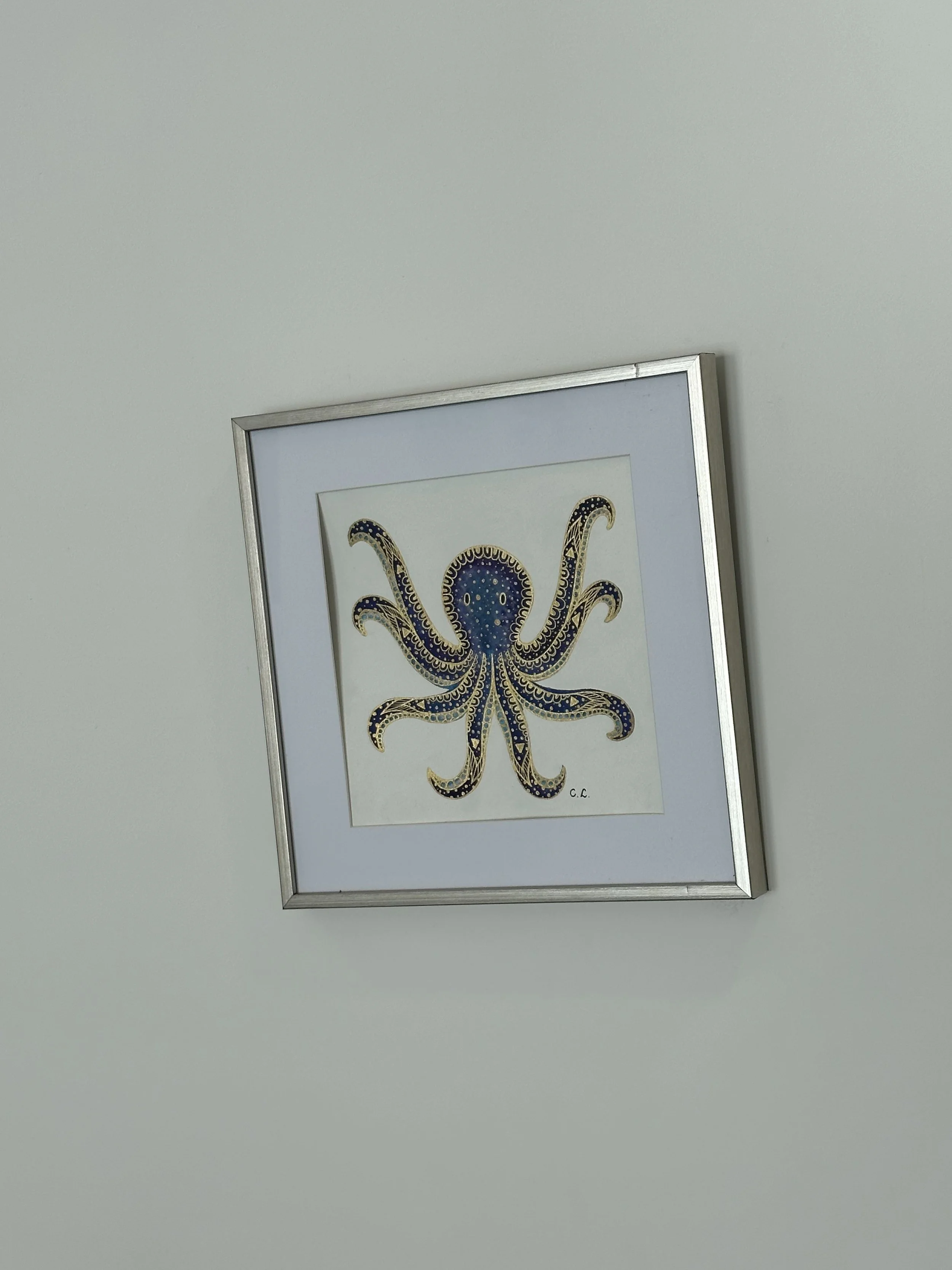 Framed artwork of an octopus with intricate patterns on a white wall.