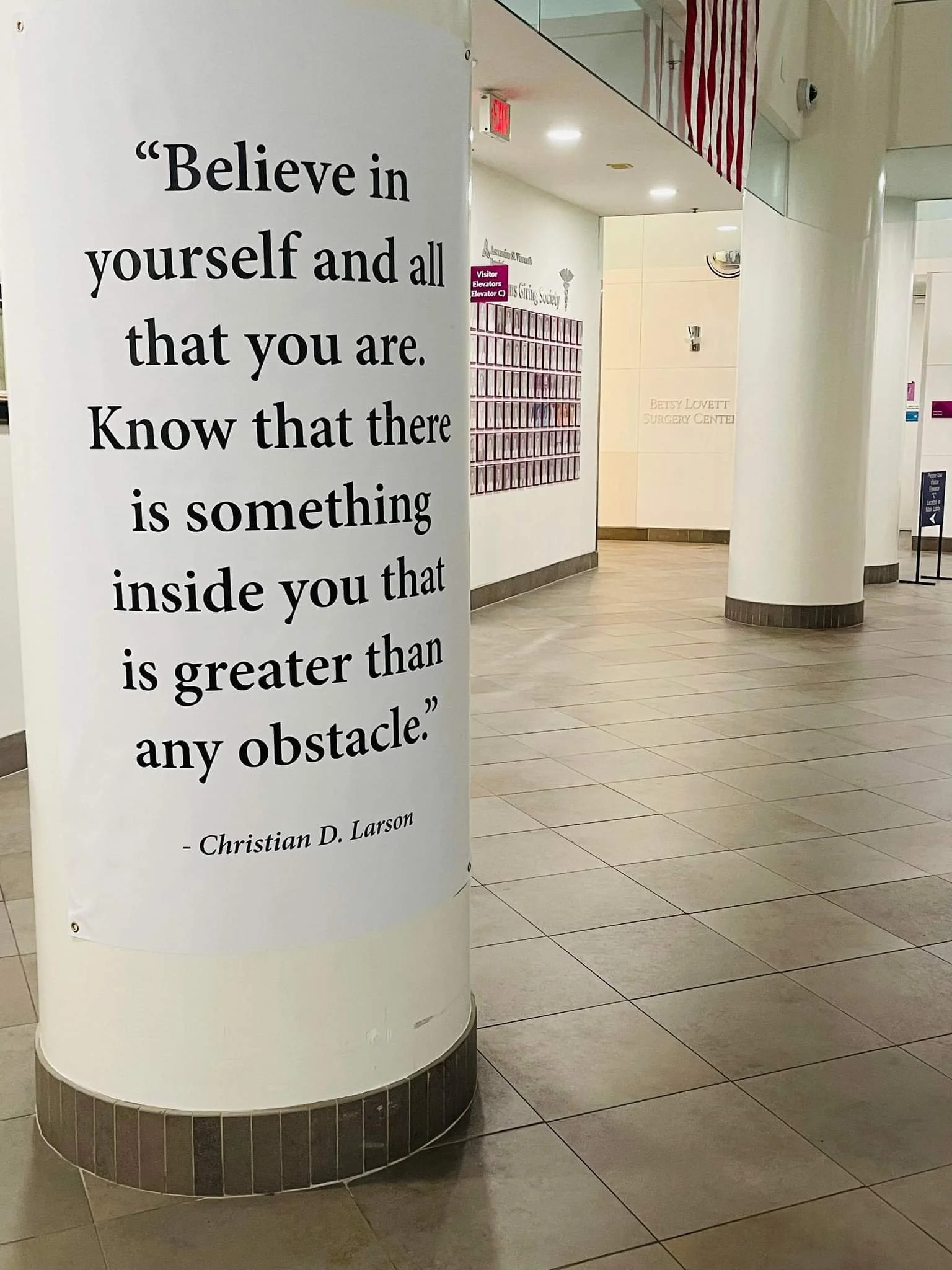 Inspirational quote on a pillar in a hospital lobby reads: 'Believe in yourself and all that you are. Know that there is something inside you that is greater than any obstacle.' - Christian D. Larson.