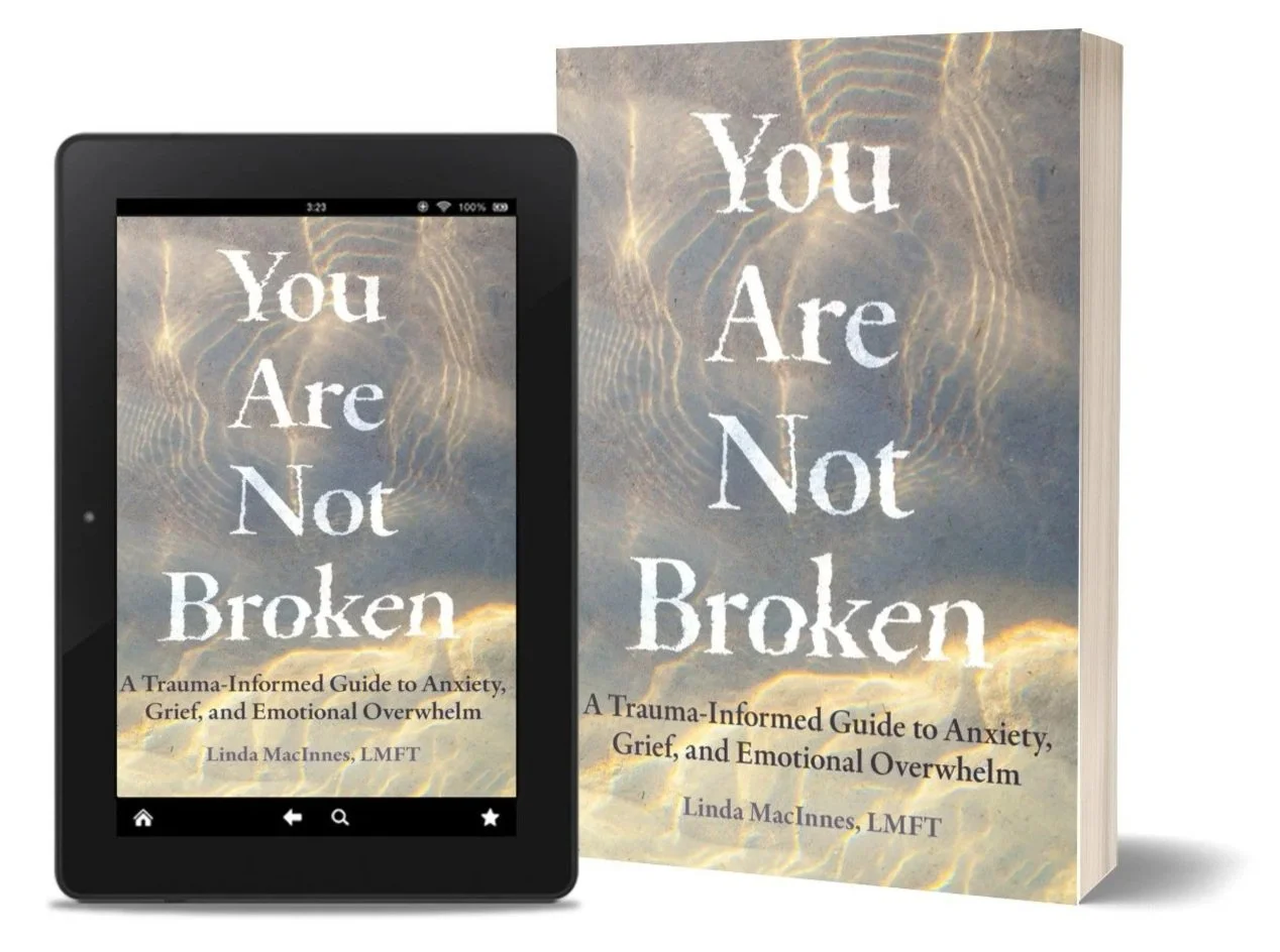 A physical book and an e-book displayed on a tablet, both titled "You Are Not Broken," with the subtitle "A Trauma-Informed Guide to Anxiety, Grief, and Emotional Overwhelm," authored by Linda MacInnes, LMFT.