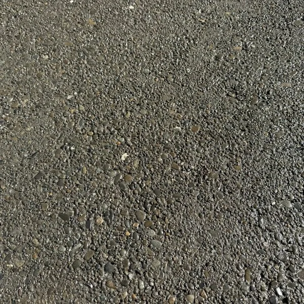 Close-up of a textured asphalt road surface with small stones and pebbles.