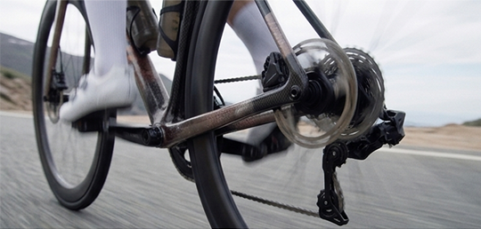 Close-up of a bicycle's gear and chain moving on a road.