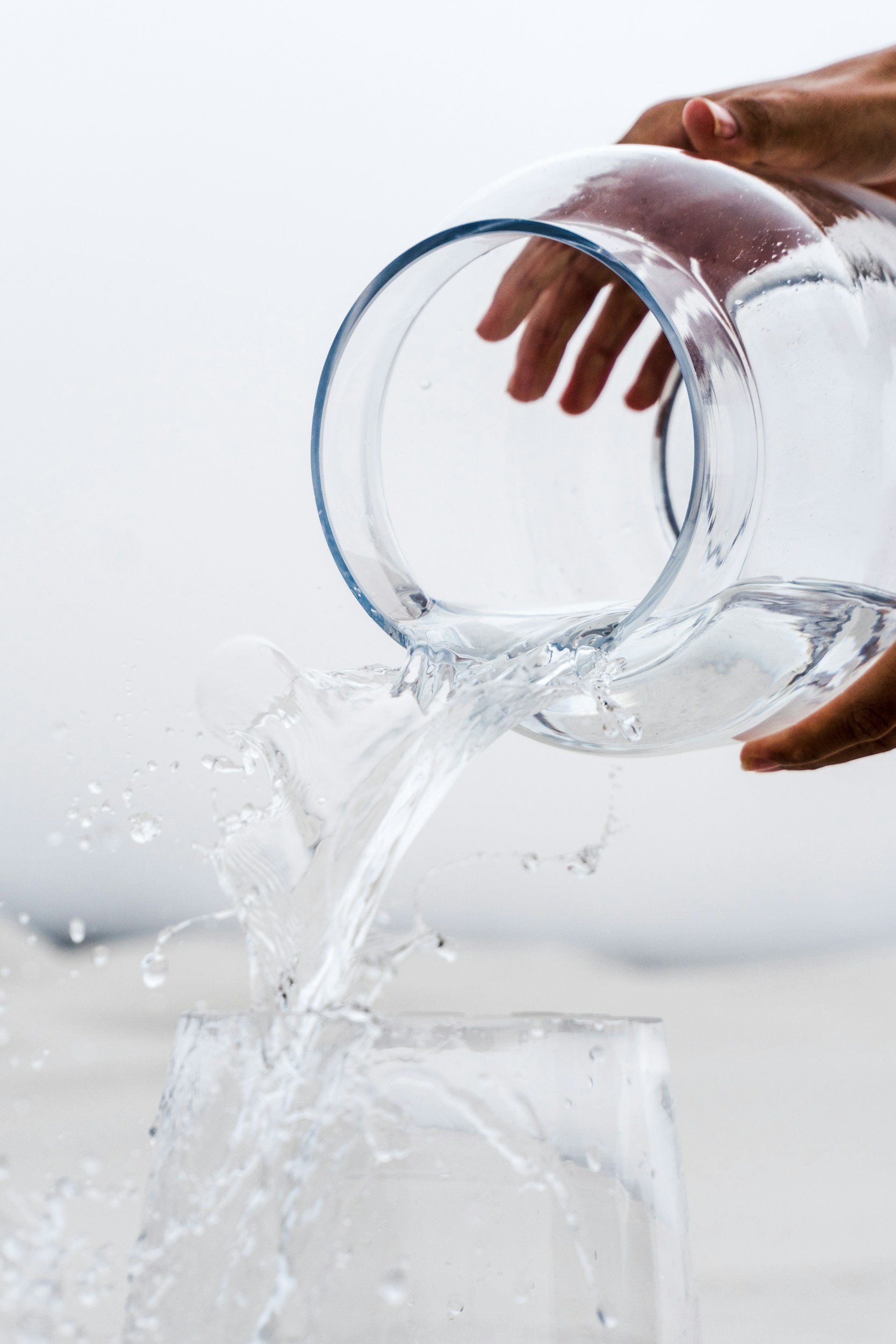 A person pouring water of out a glass jar