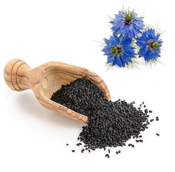 A wooden scoop spilling black cumin seeds next to a cluster of blue cornflower blossoms.