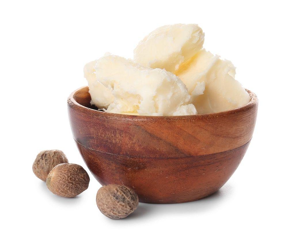 Bowl of mashed potatoes with three whole allspice berries beside it on white background.
