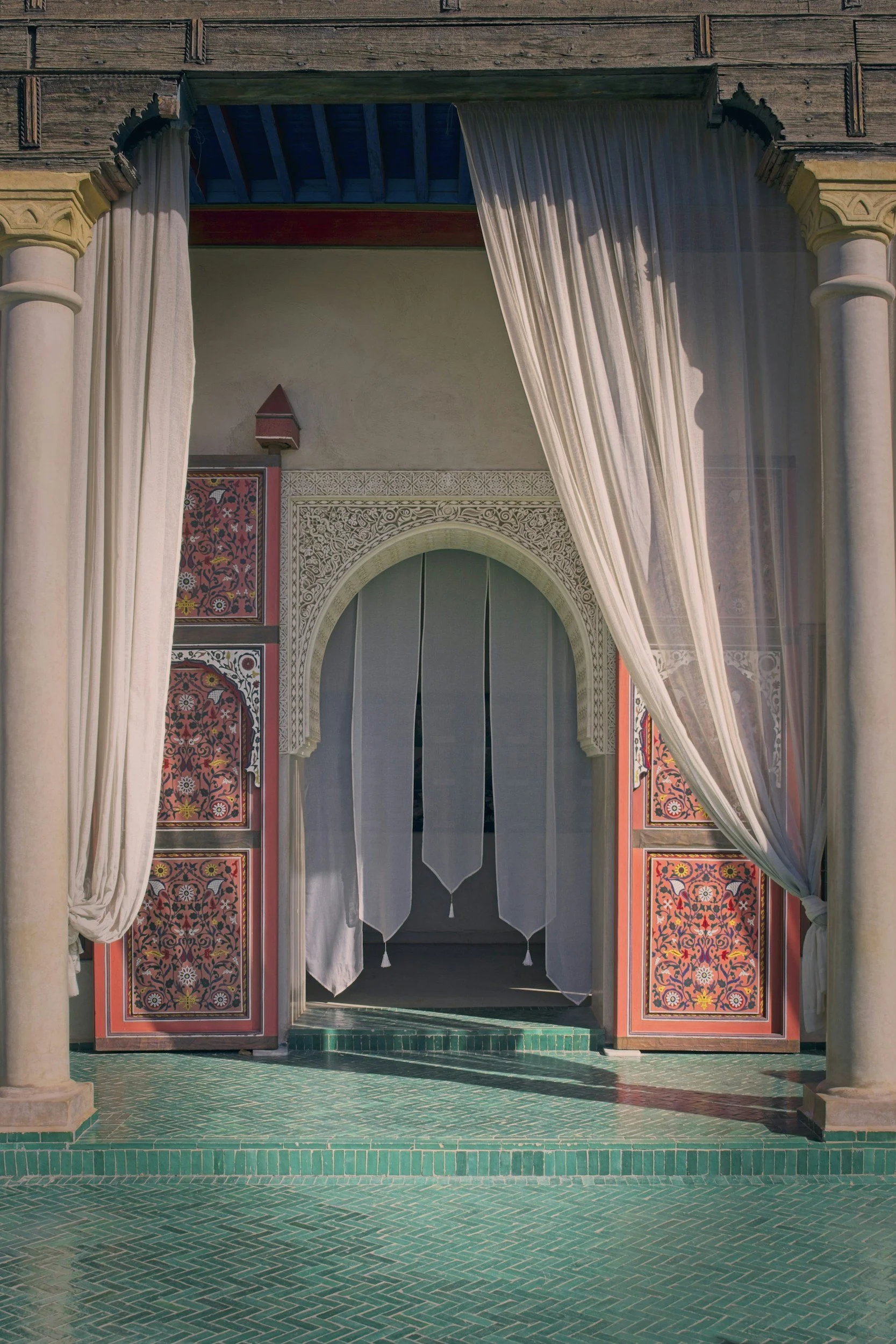 luxurious moorish type doorway with large draped curtains and arched intricately painted doorway and tiled floor, stone columns