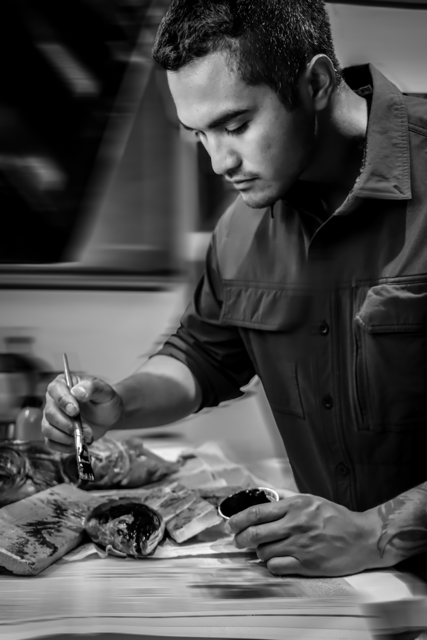 Jason Bero in a dark shirt preparing or arranging fish on a surface.