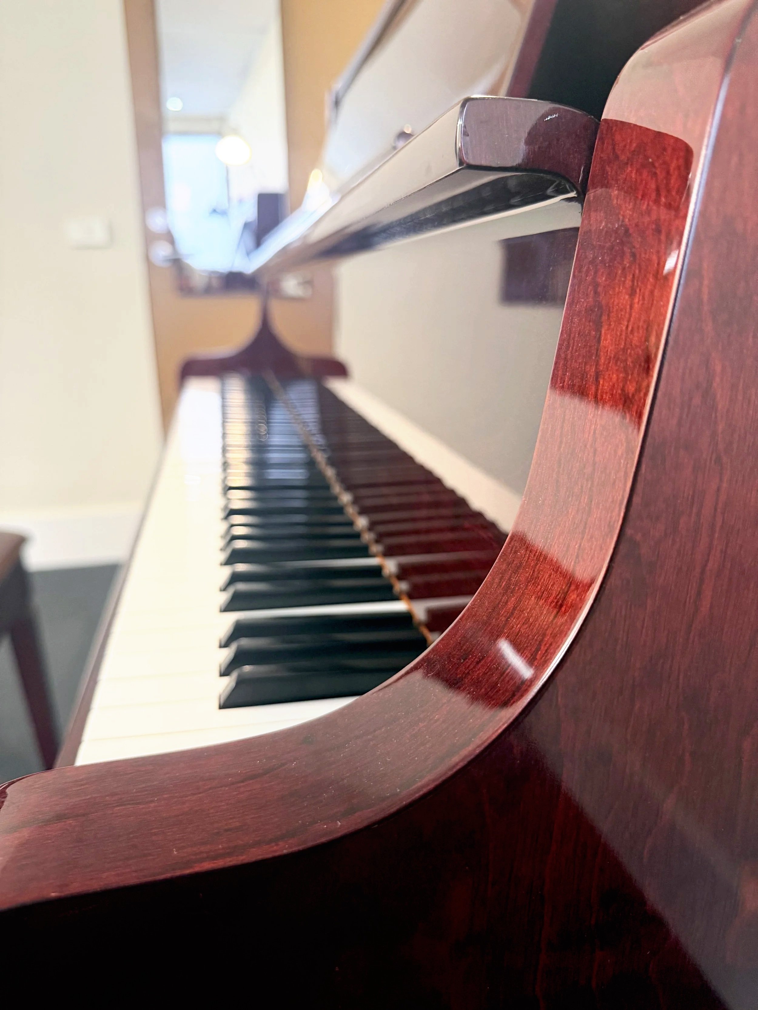 Close-up of a piano keyboard through a round wooden frame, showing black and white keys.