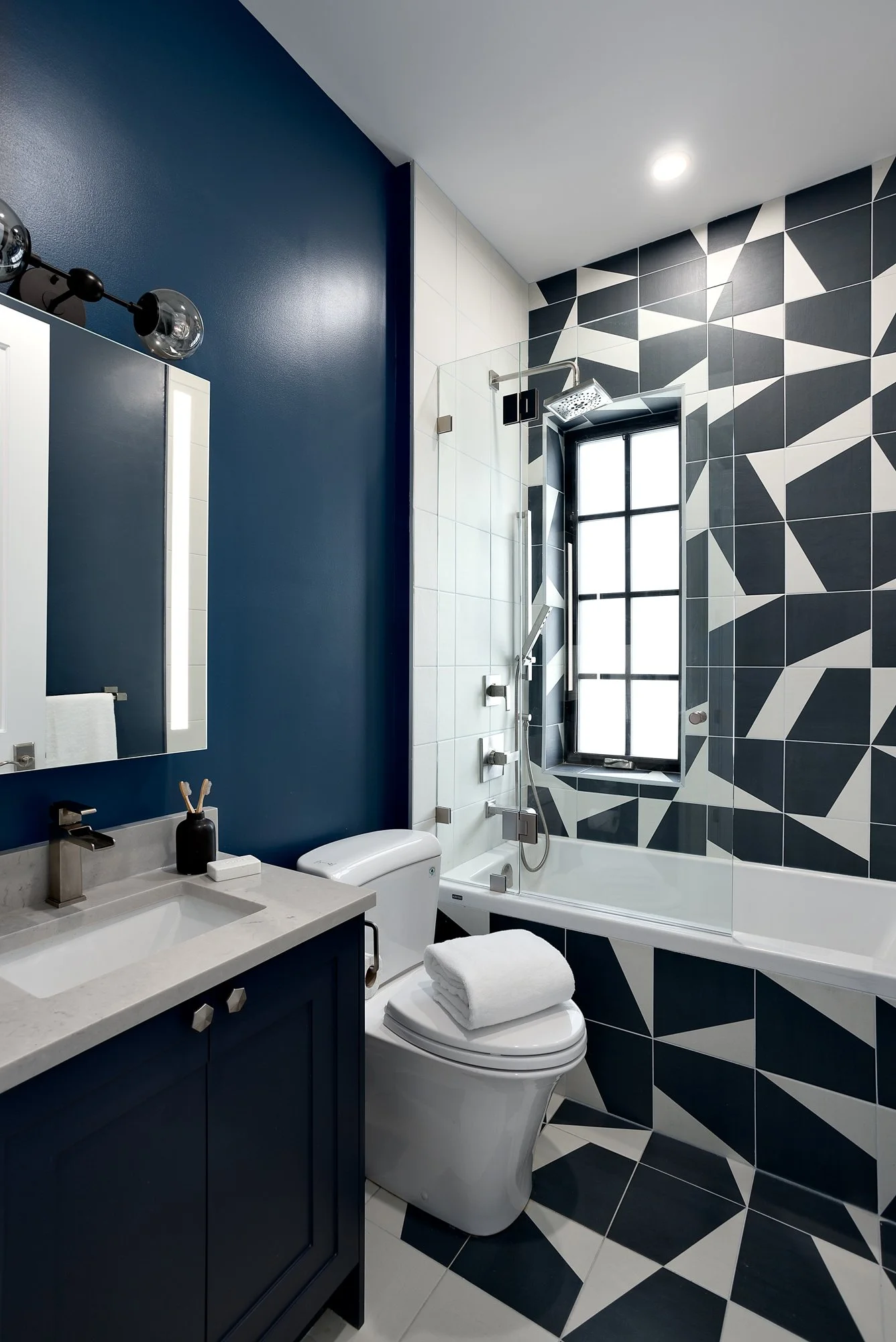 Bold bathroom design featuring a black and white geometric tile shower surround paired with deep navy blue walls for high-contrast impact.