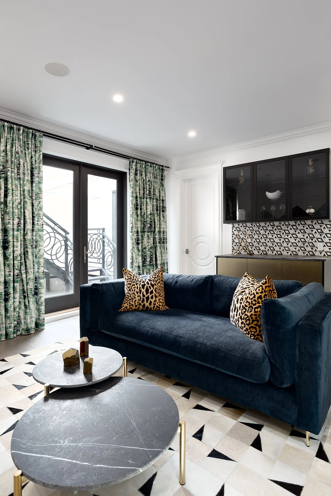 Chic sitting room featuring a navy velvet sofa, leopard print pillows, and bold patterned curtains in a dynamic family environment.